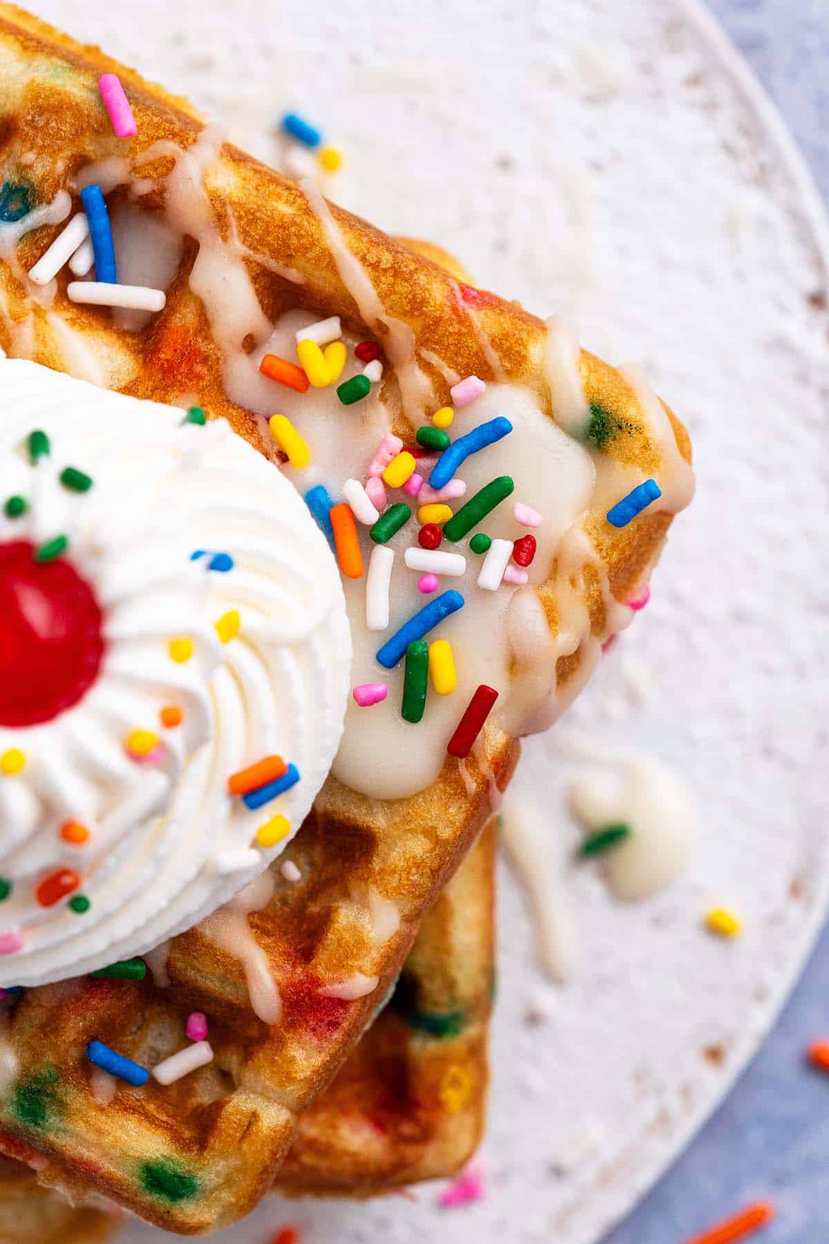 close up overhead of funfetti waffles with vanilla icing