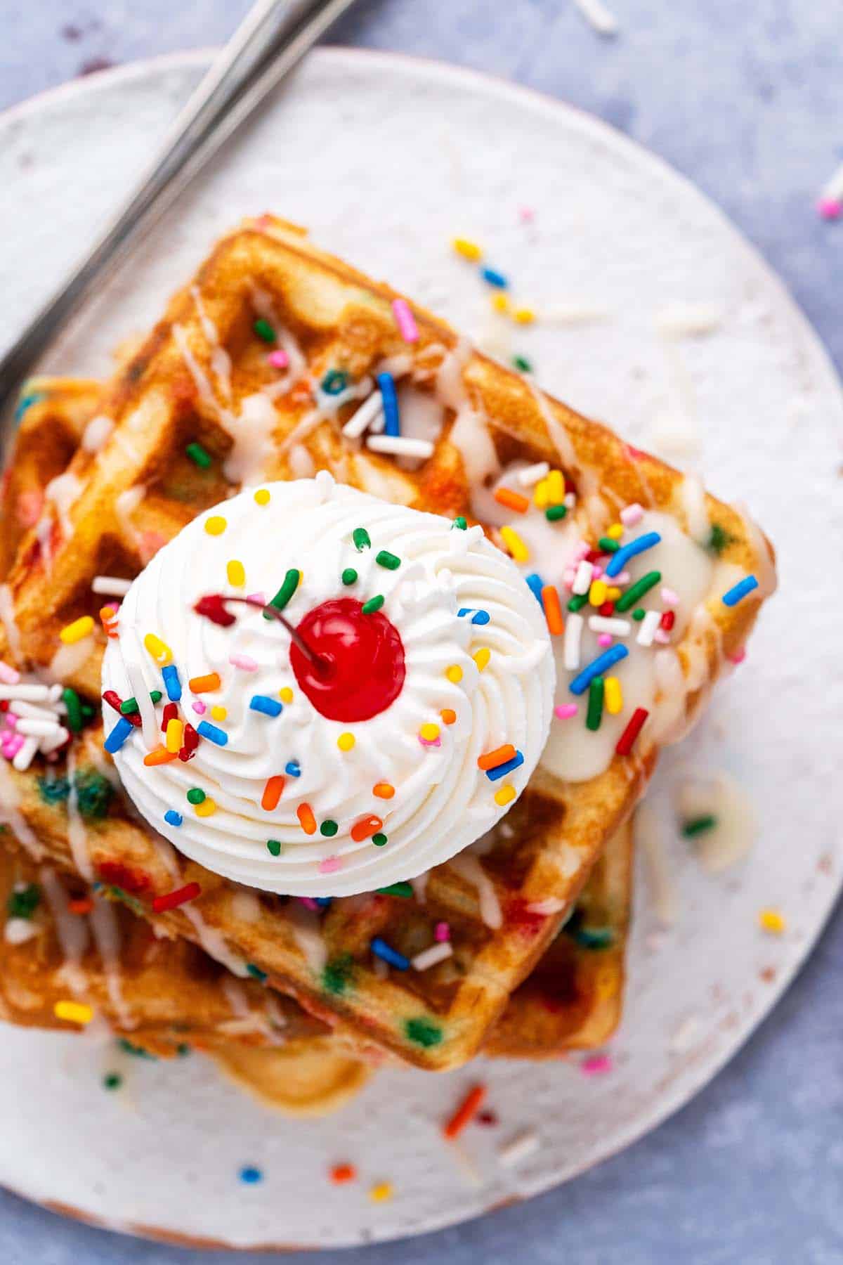 close up top view of birthday cake waffles with whipped cream and cherry