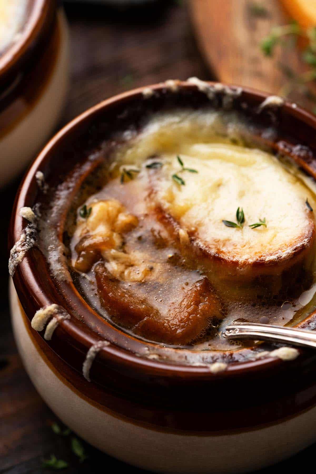 crock of french onion soup au gratin with spoon