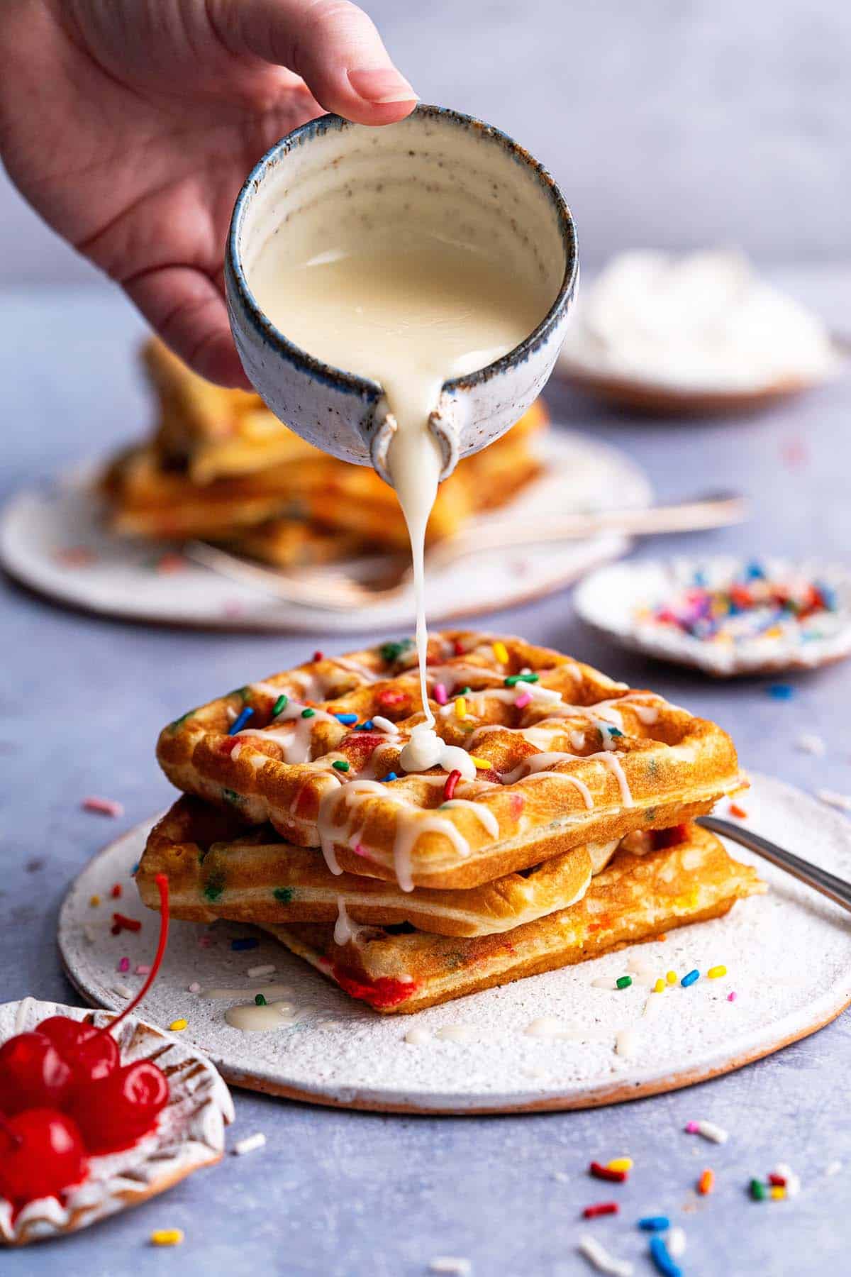 drizzling vanilla glaze on birthday cake waffles