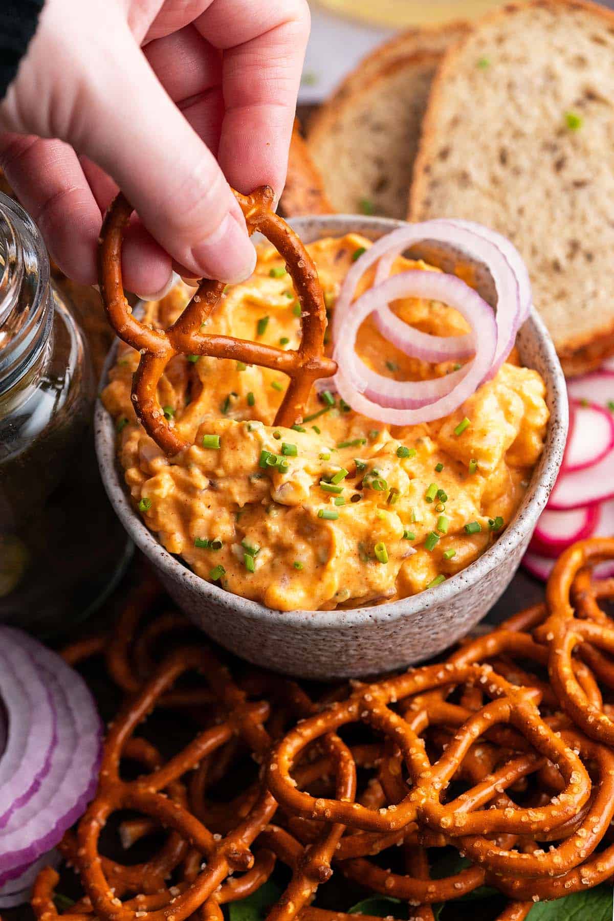 hand dipping pretzel into bavarian beer cheese dip