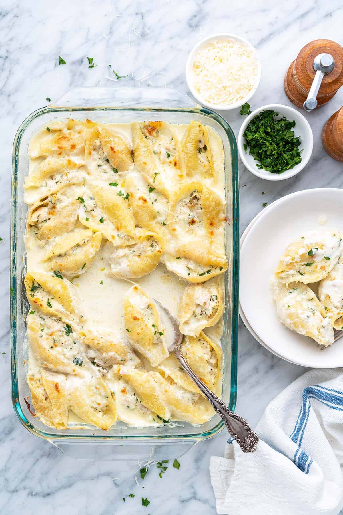 chicken stuffed shells with alfredo sauce and ricotta in glass casserole dish on marble counter