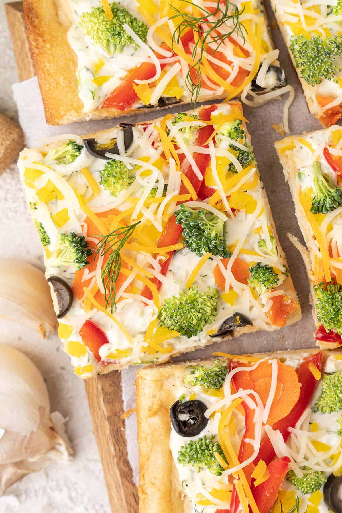 close up top view of squares of crescent roll veggie pizza with ranch
