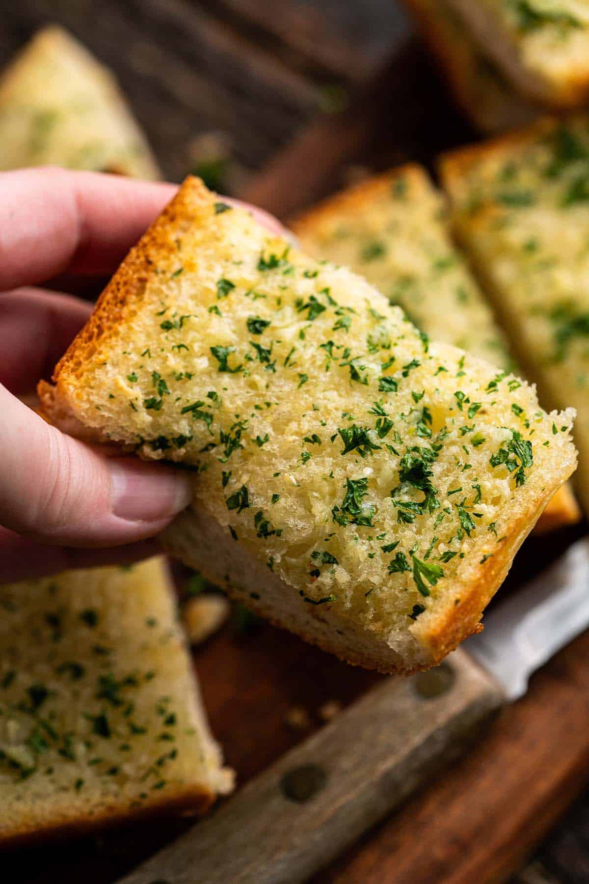 close up of hand holding soft garlic bread