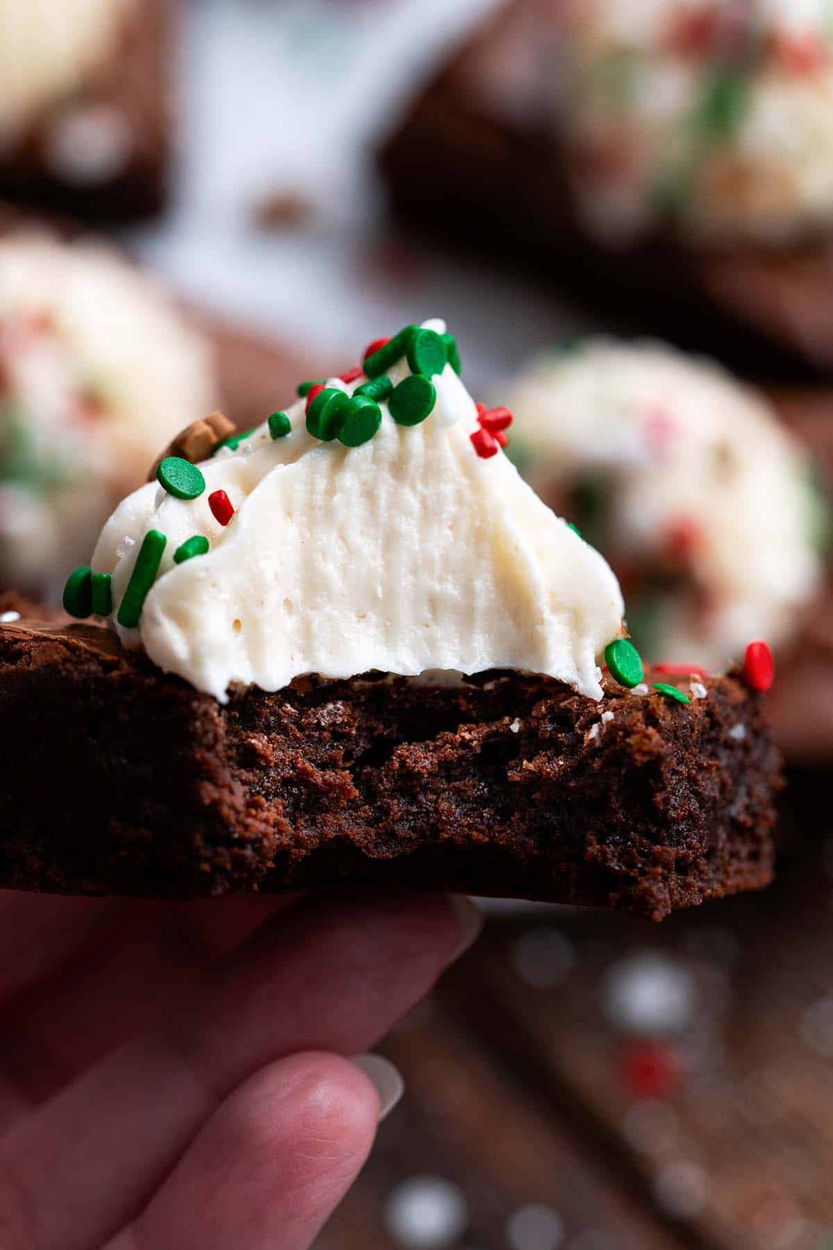 hand holding gingerbread brownie decorated for christmas with bite to show fudgy texture