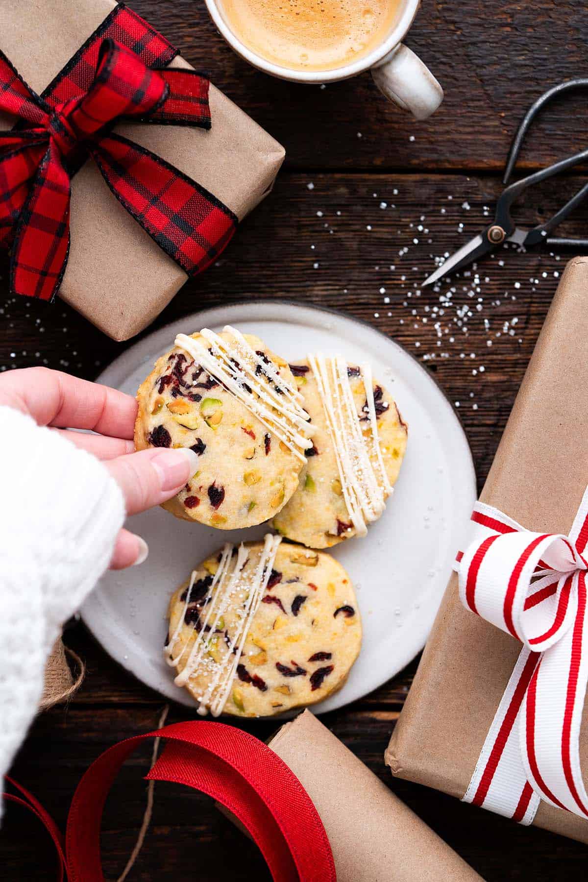 hand picking up christmas shortbread cookie from plate