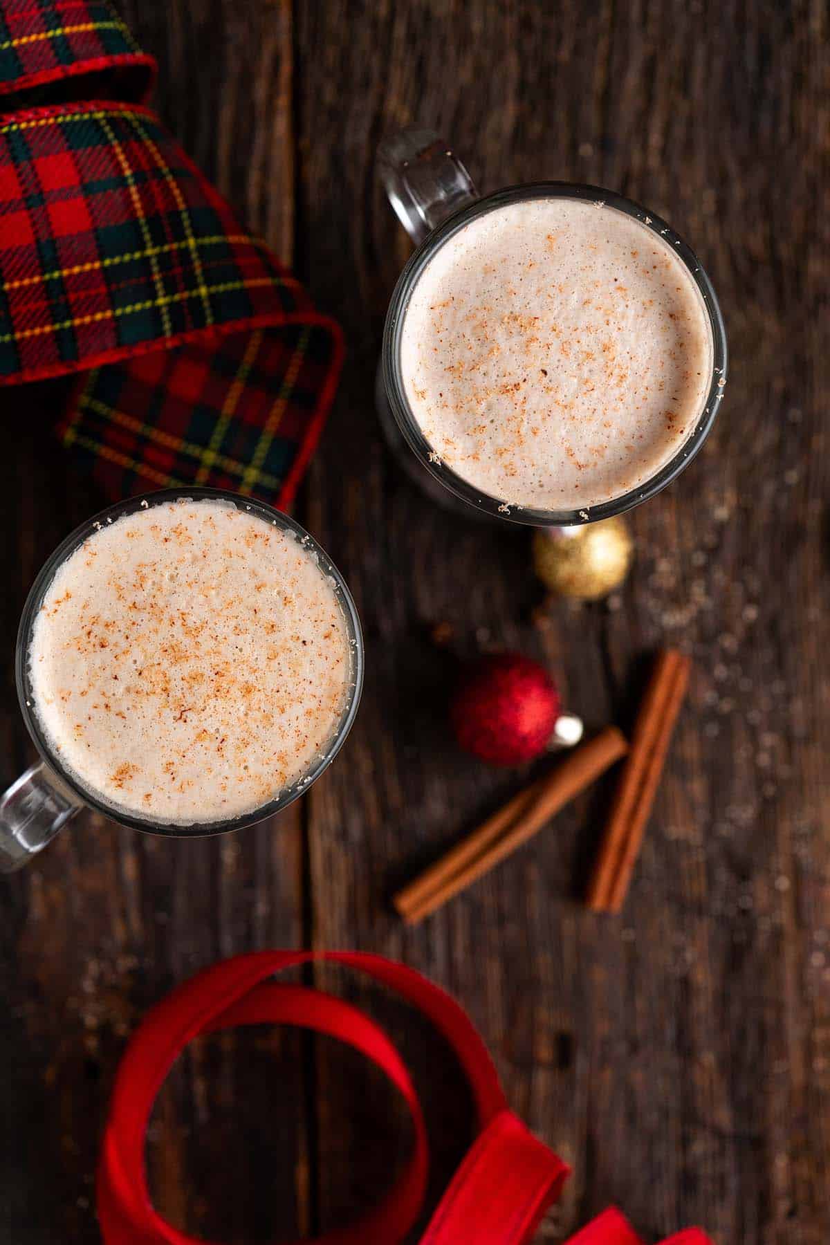 overhead view of 2 mugs of tom & jerry christmas cocktail