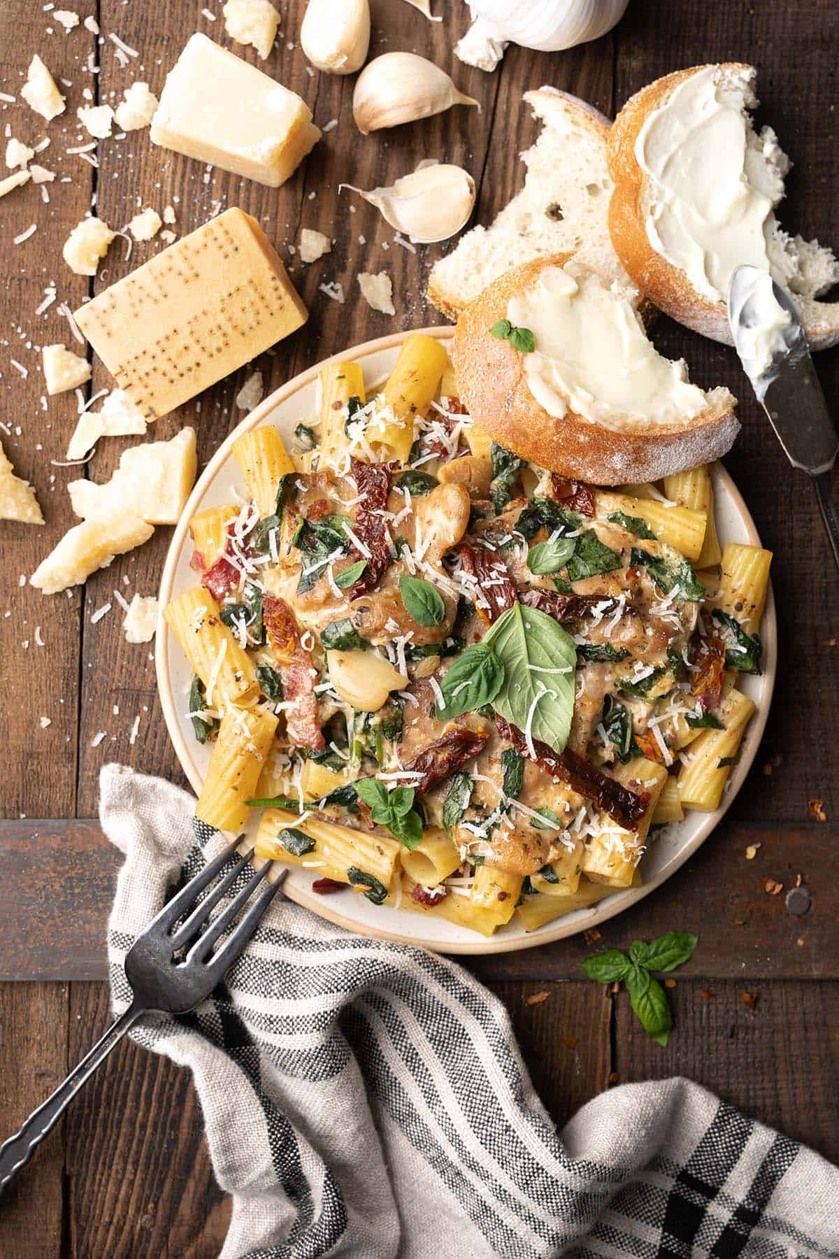 plate of tuscan chicken pasta with rigatoni and buttered bread