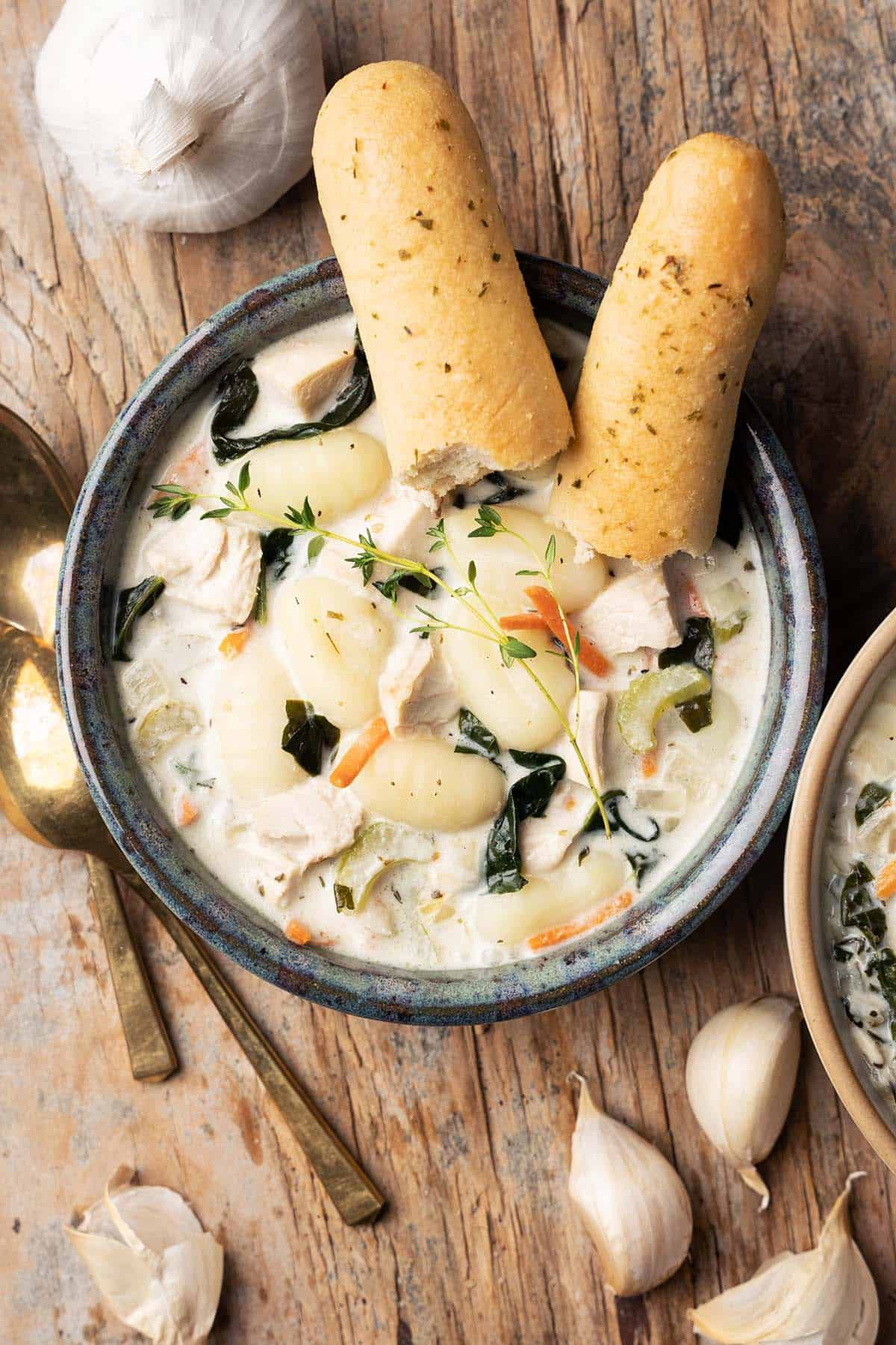 top view of bowls of creamy potato gnocchi soup with chicken with breadsticks