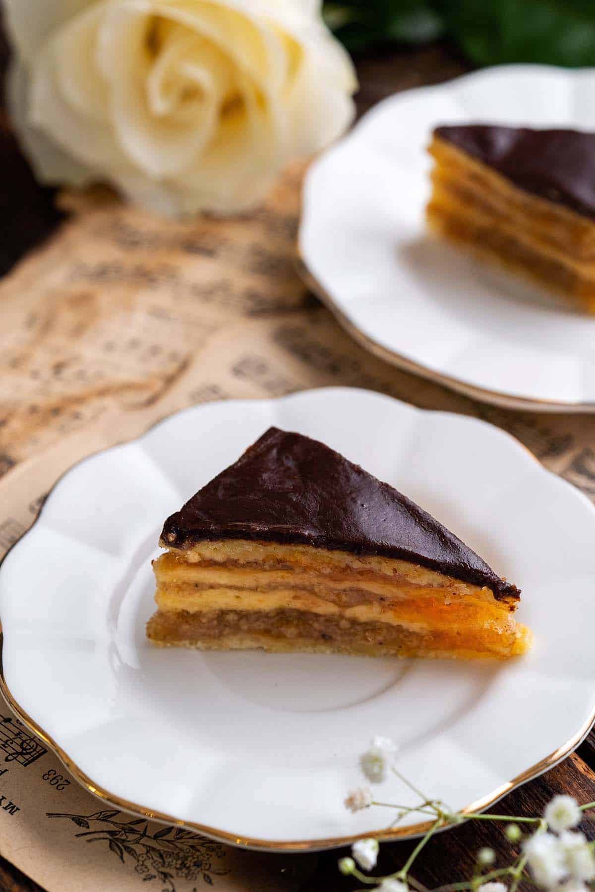 close up front view of slice of Zserbó on white dessert plate with gold trim