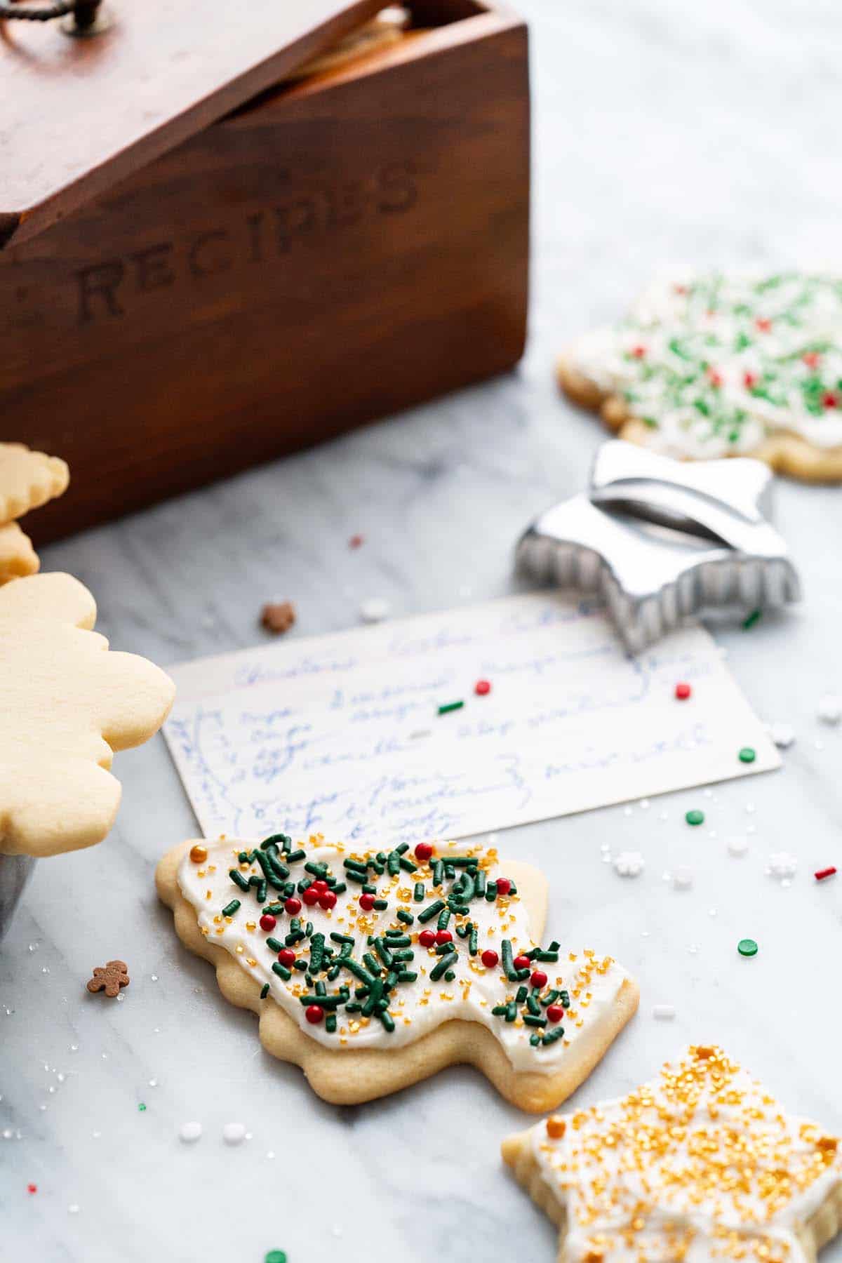 decorated christmas tree cutout cookie with vintage recipe box behind