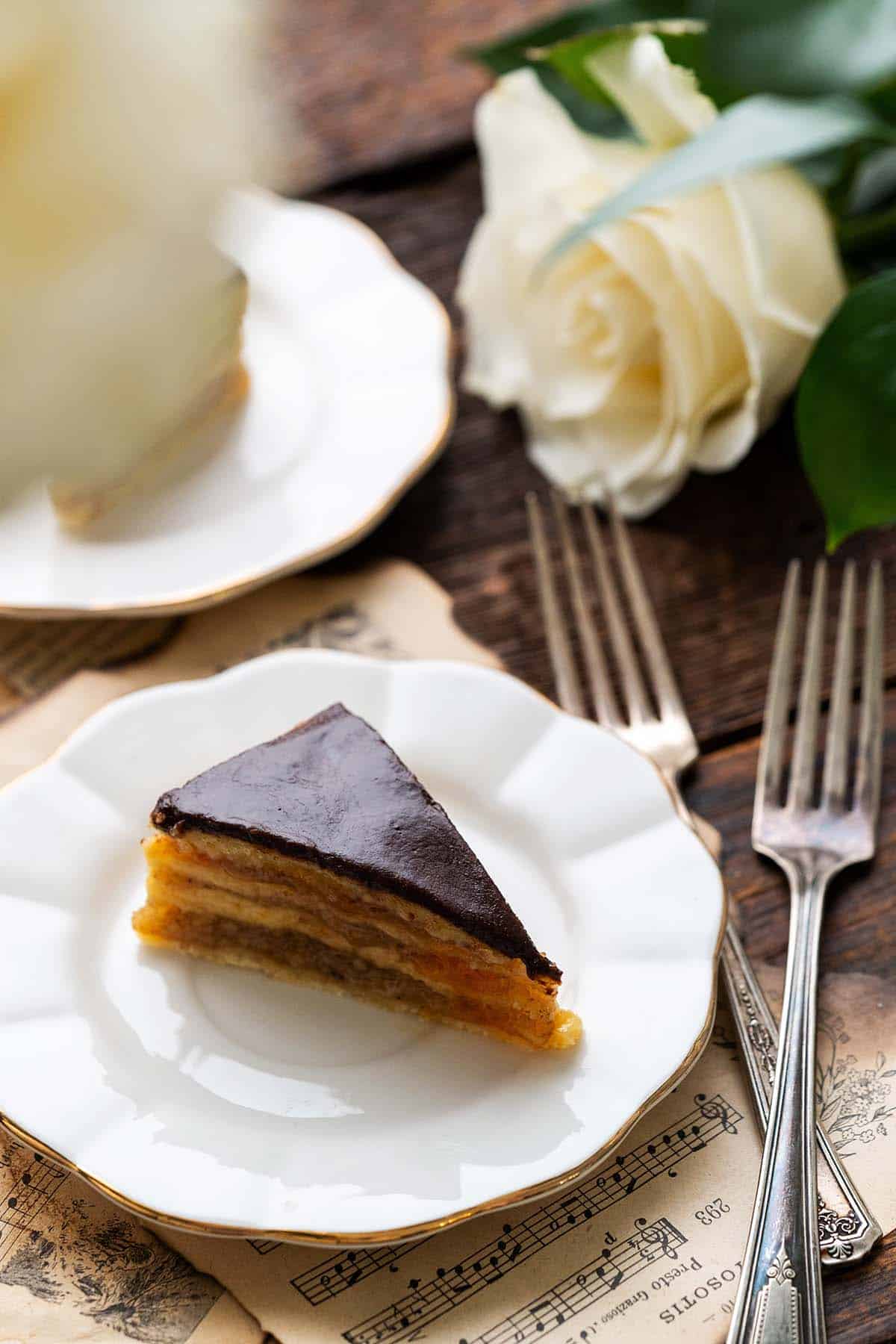 front view of zserbo cake slice on white plate with roses