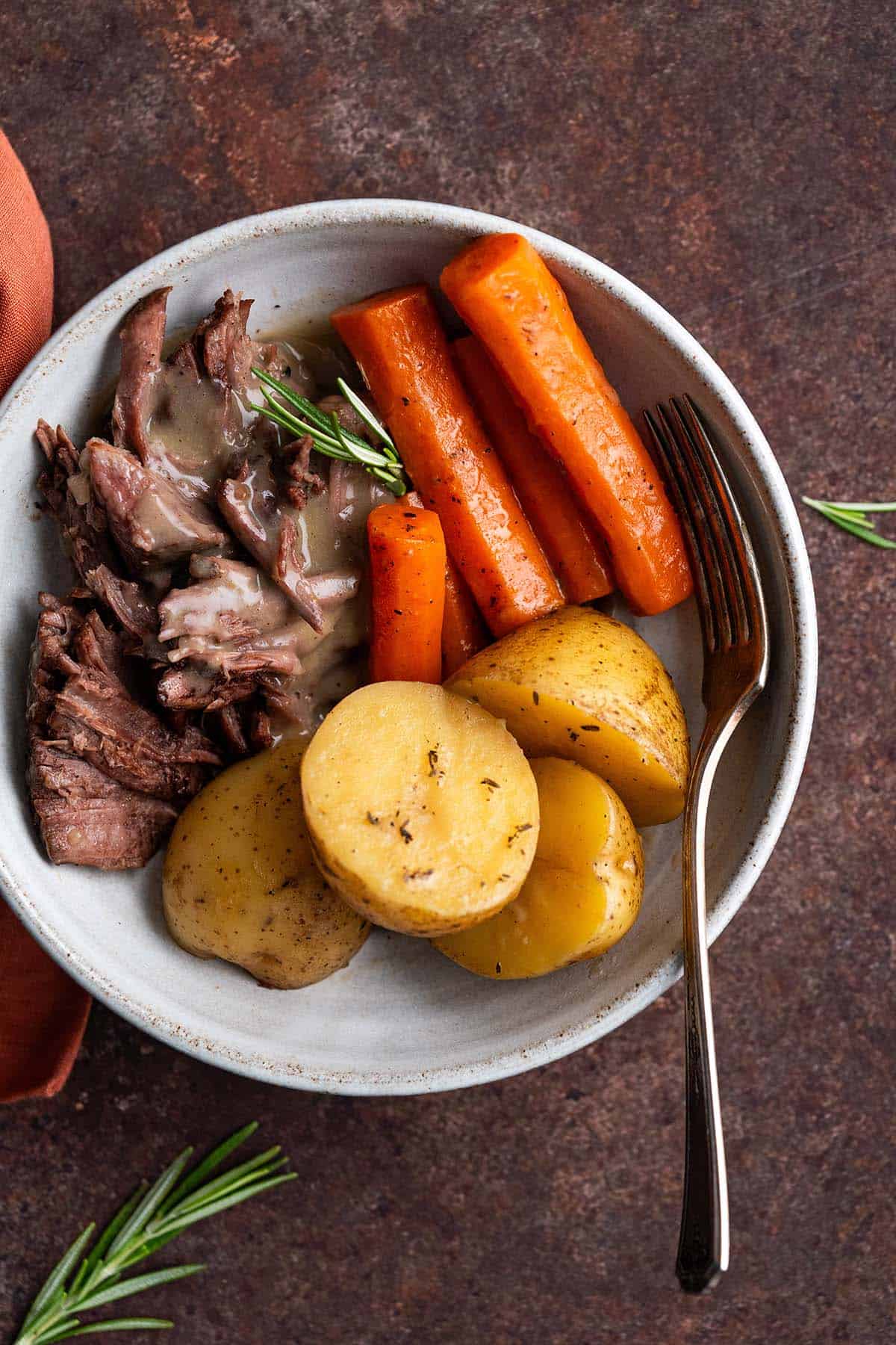 plate of yankee pot roast meal cooked in cast iron dutch oven with gravy