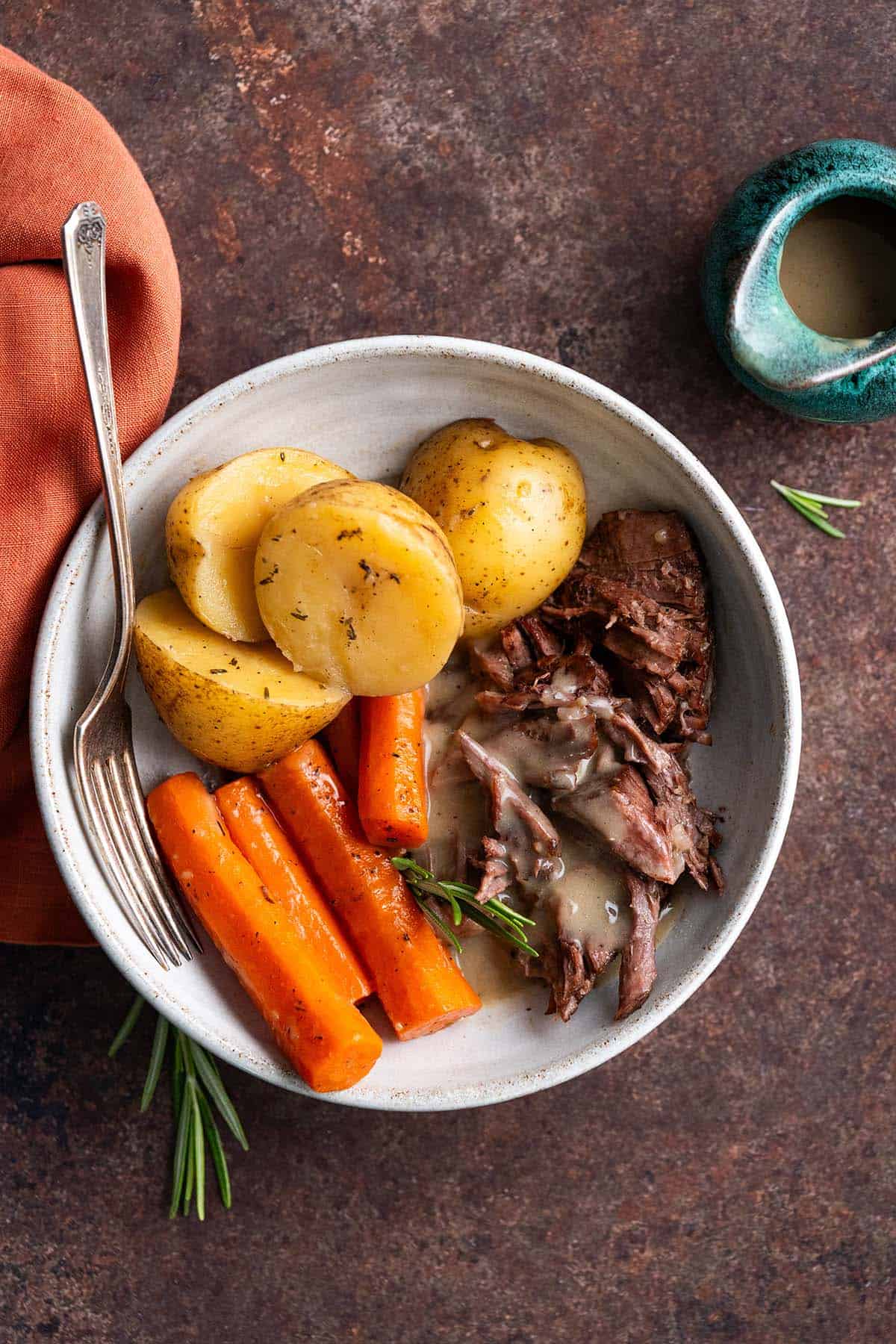 plated serving of dutch oven chuck steak with gravy and vegetales