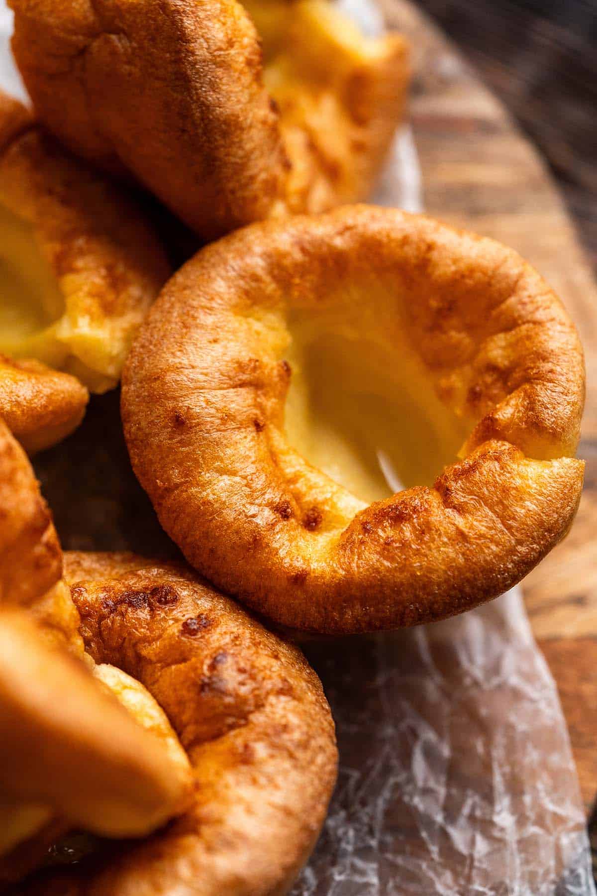 close up of golden yorkshire puddings on wooden board