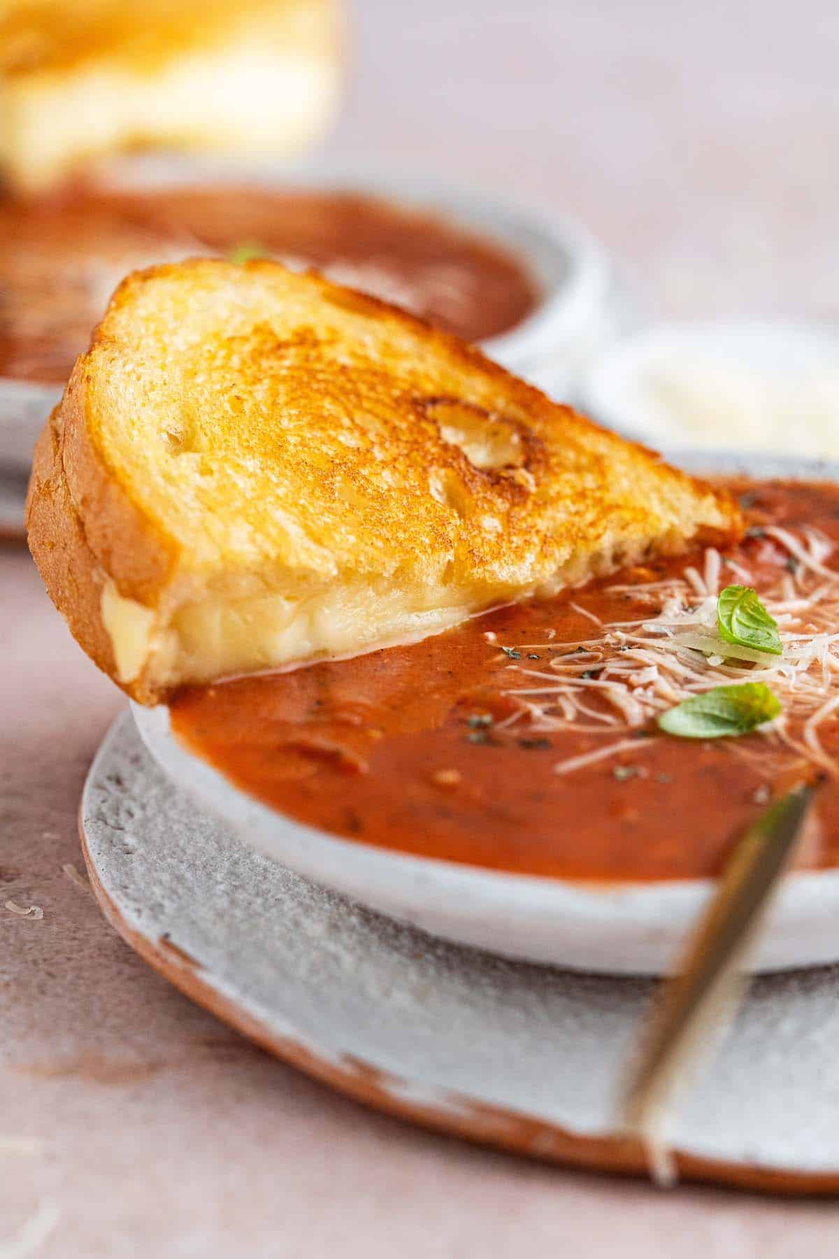 dipping toasted cheese sandwich into tomato bisque