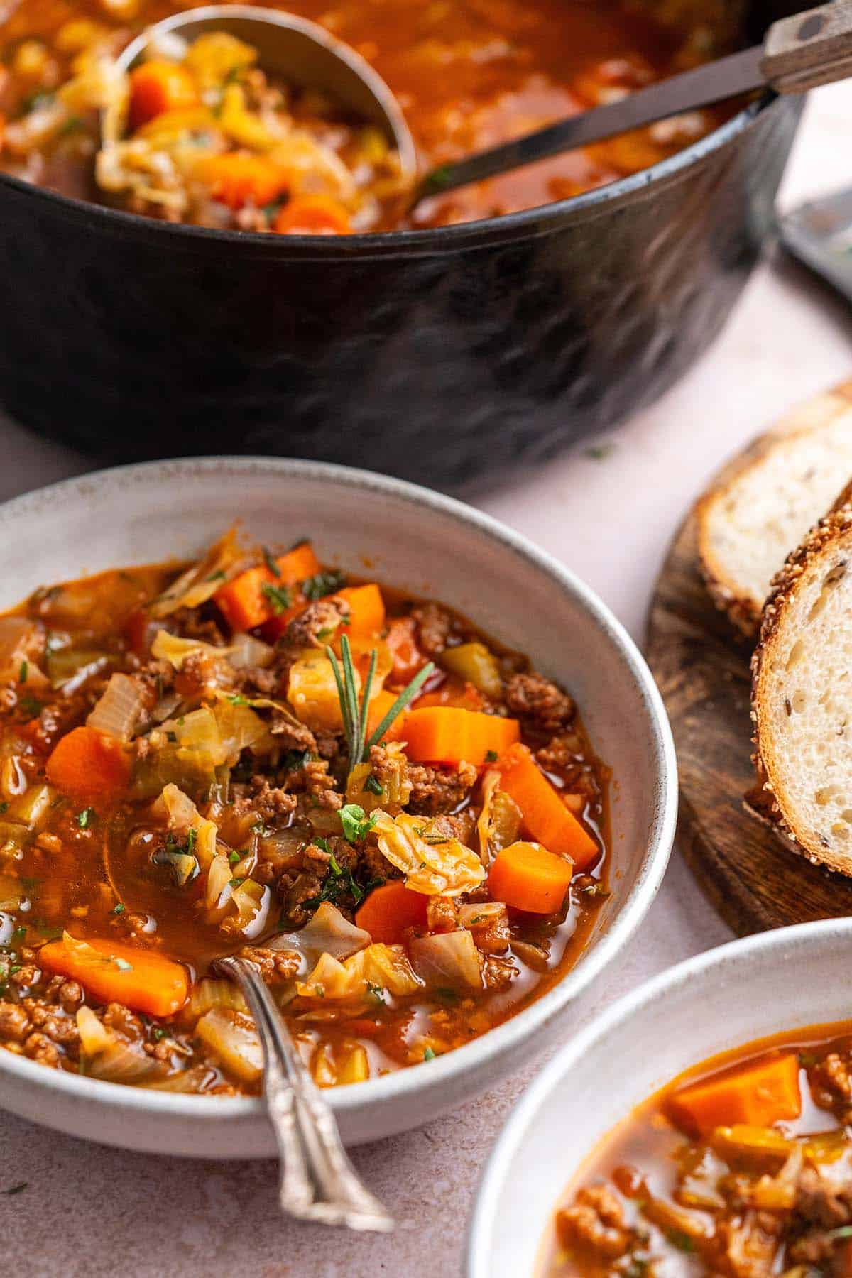 hamburger cabbage soup in bowl with dutch oven in background