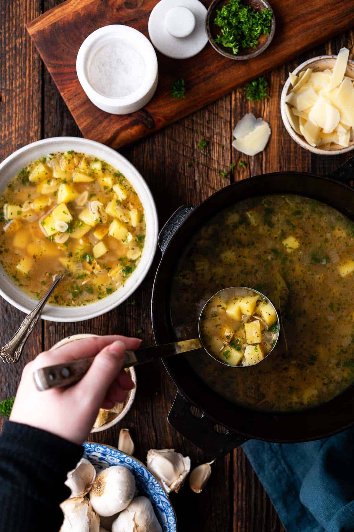 hand ladling czech garlic soup out of dutch oven