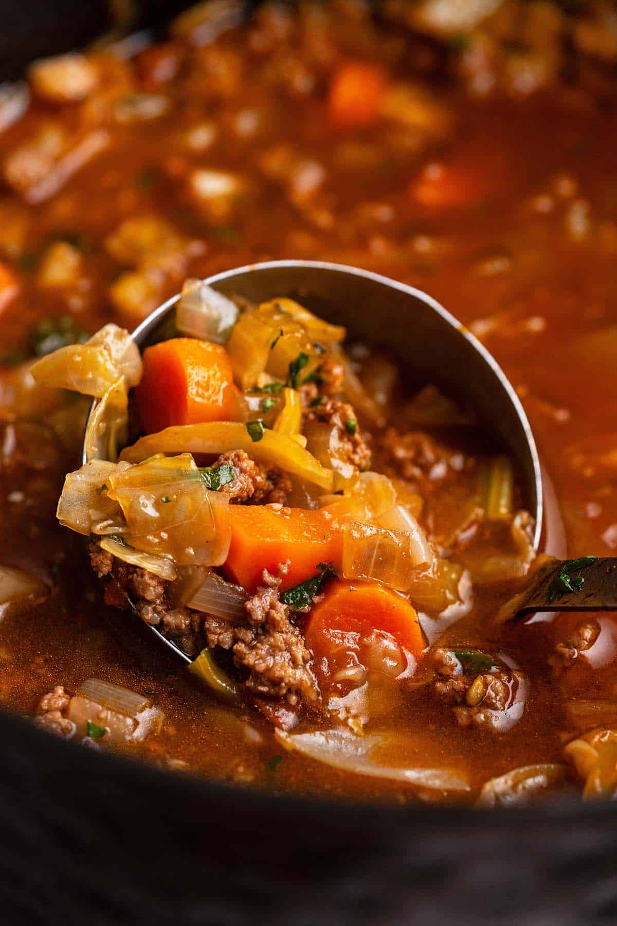 ladle of cabbage soup with vegetables and ground beef