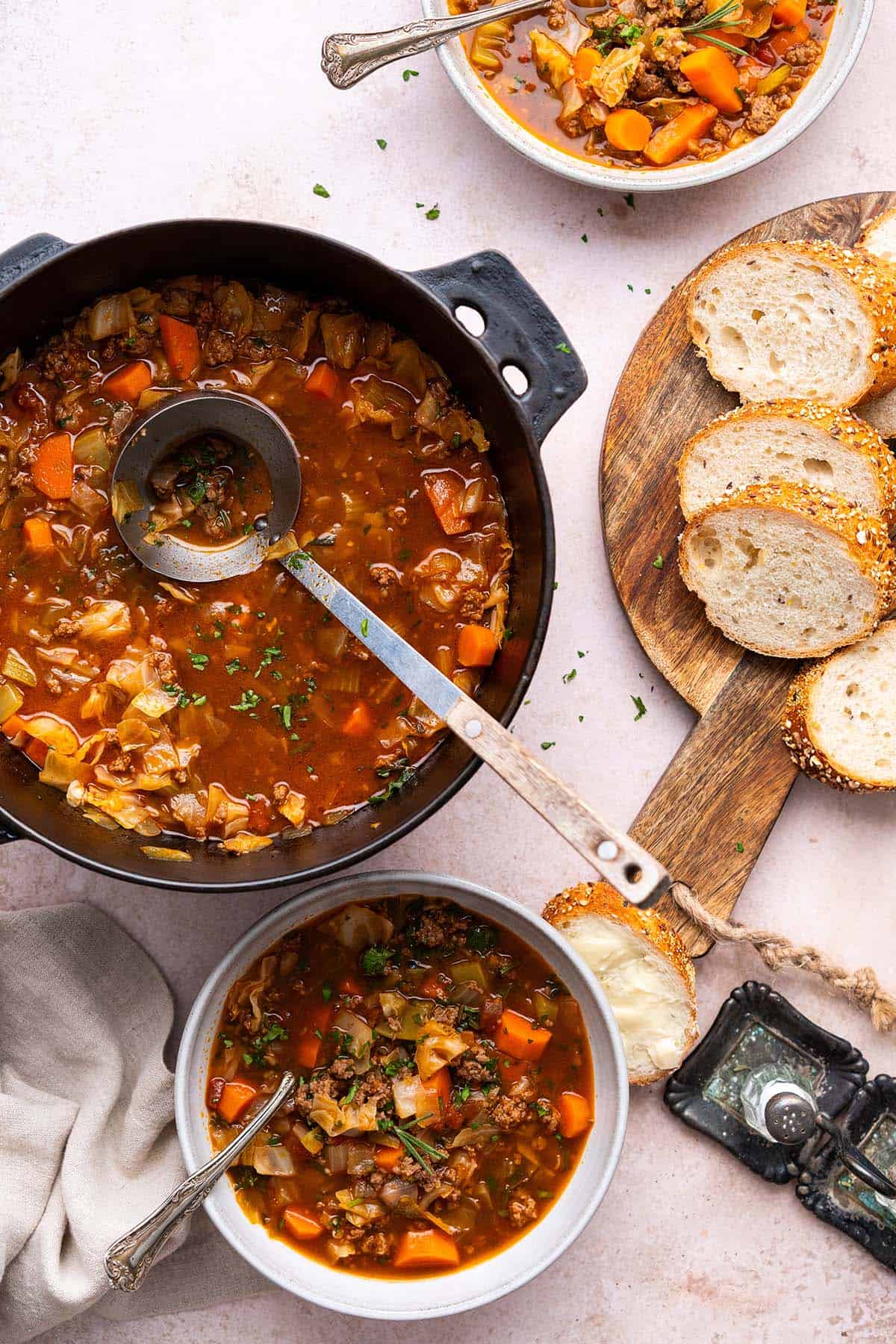 pot of vegetable soup with cabbage and ground beef with sliced bread