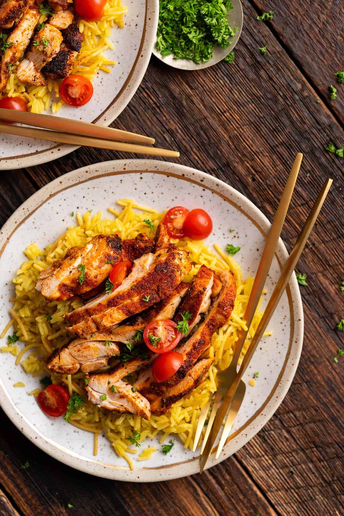 top view of plated chicken and rice meal on dark wooden table