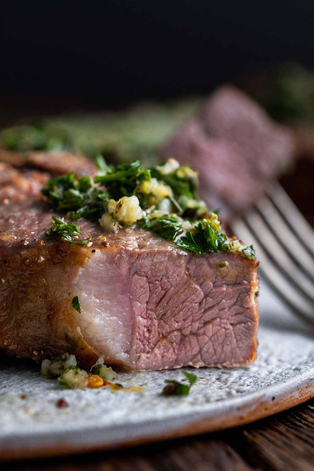 close up of perfectly cooked lamb chop with bite cut off to show juicy meat inside