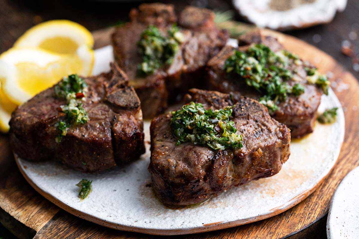 handmade pottery plate with juicy flavorful lamb chops topped with fresh herb sauce