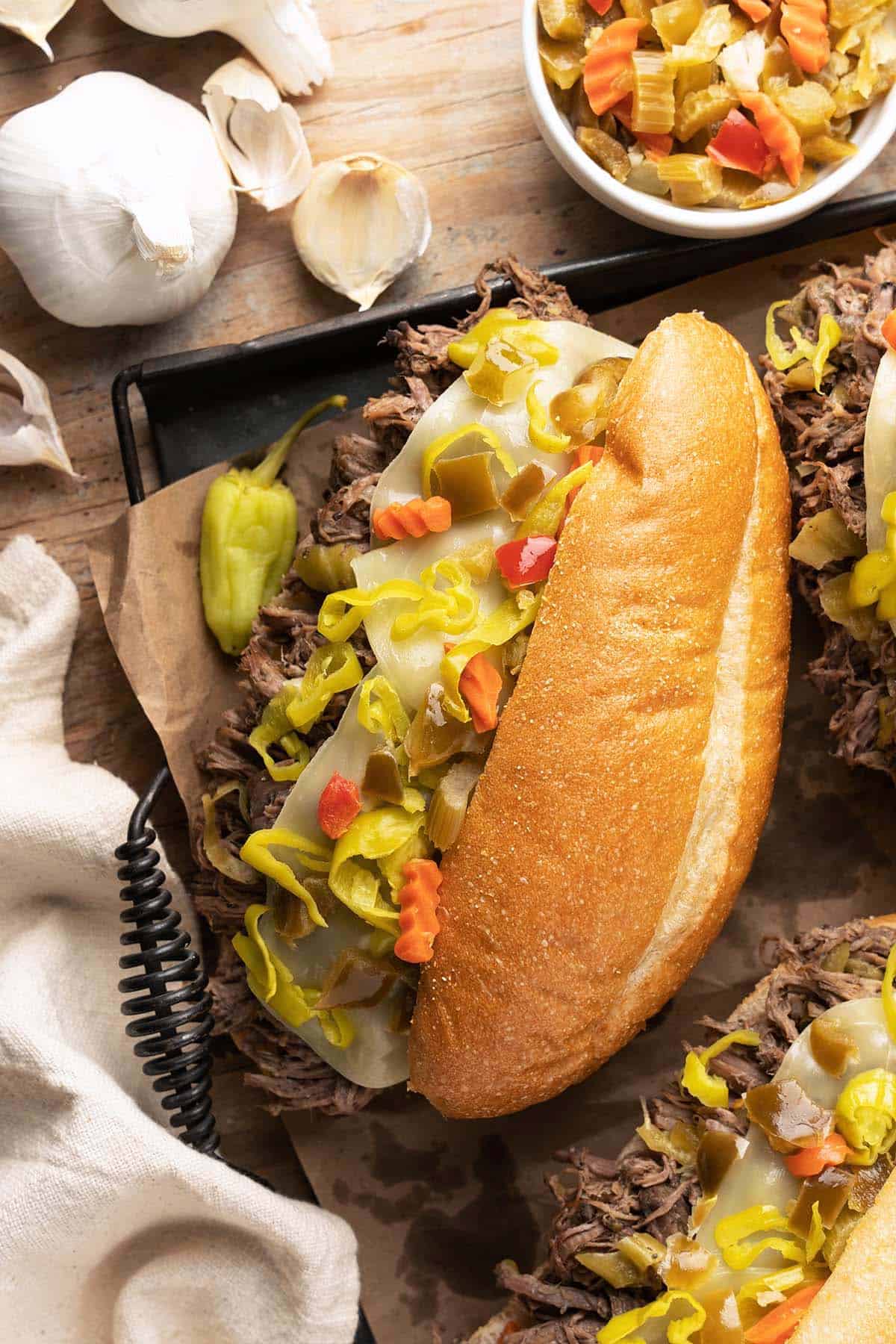 top view of italian beef sandwich recipe topped with cheese and spicy peppers