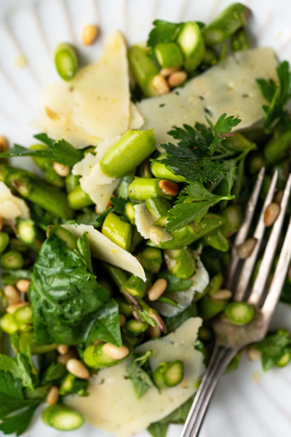 close up top view of chopped asparagus salad on plate with pine nuts and parm