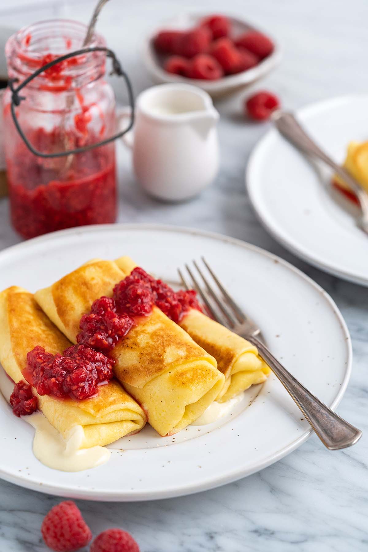 cheese blintzes on plate with raspberry sauce on top