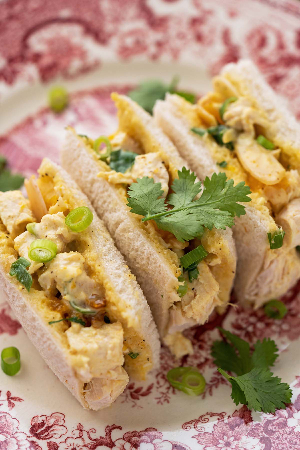 fancy finger sandwiches for afternoon tea on red and white flowered plate
