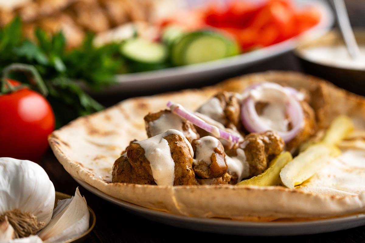 shawarma chicken on arabic flatbread with white sauce and pickles