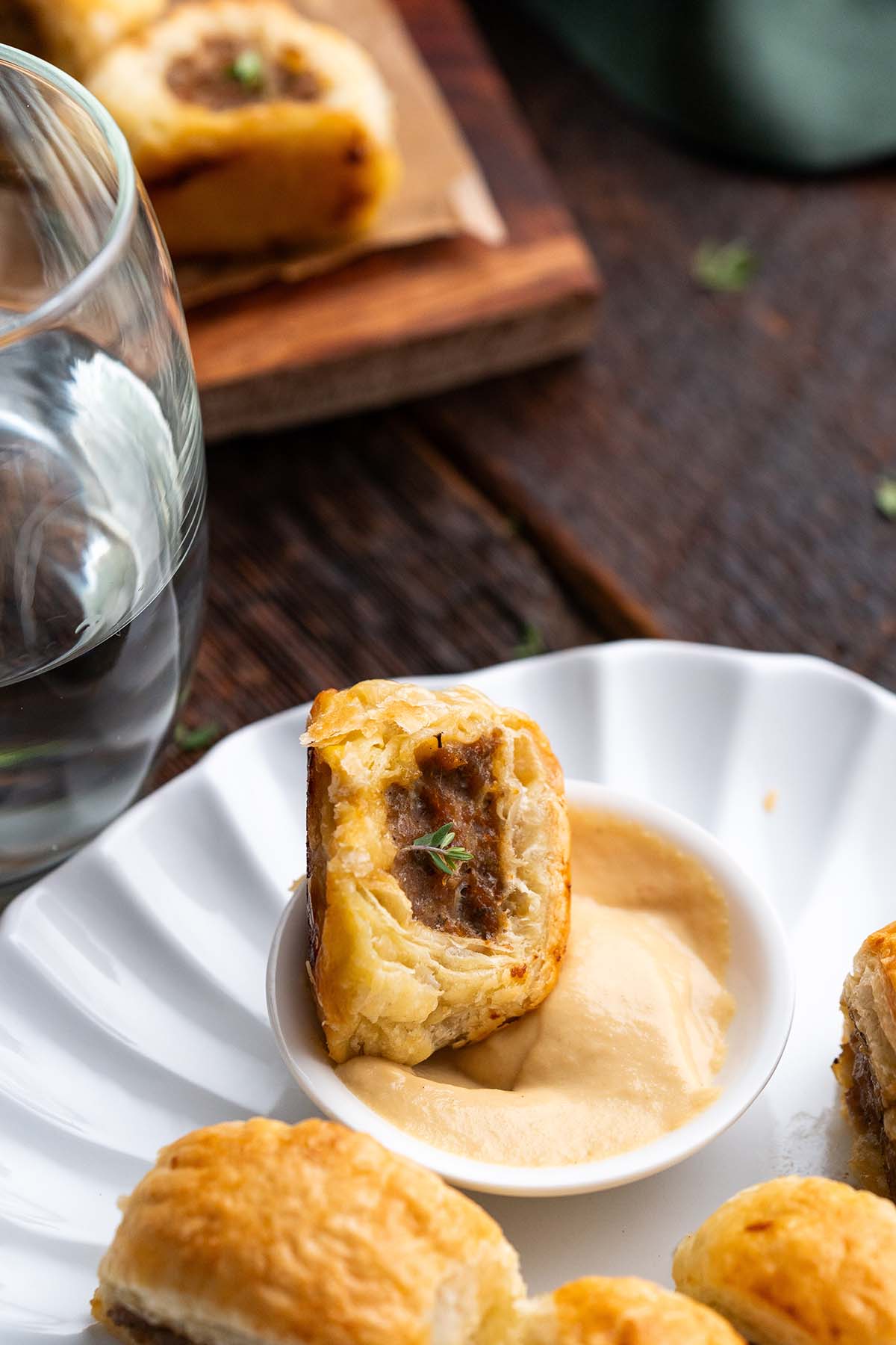 dipping mini puff pastry sausage roll in dijon mustard