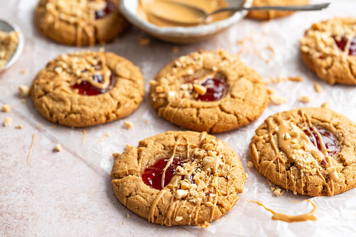 drizzling peanut butter onto cookies with jam