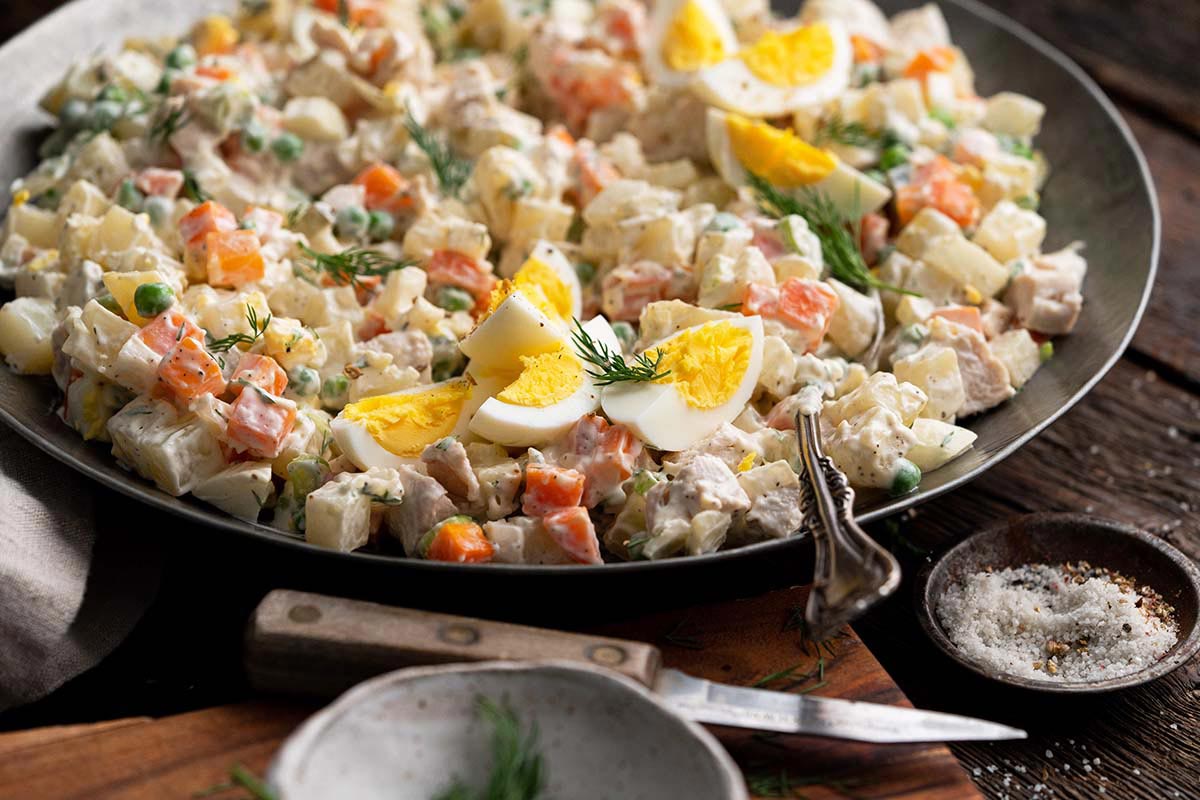 bowl with Russian potato salad with mayo on rustic wooden table