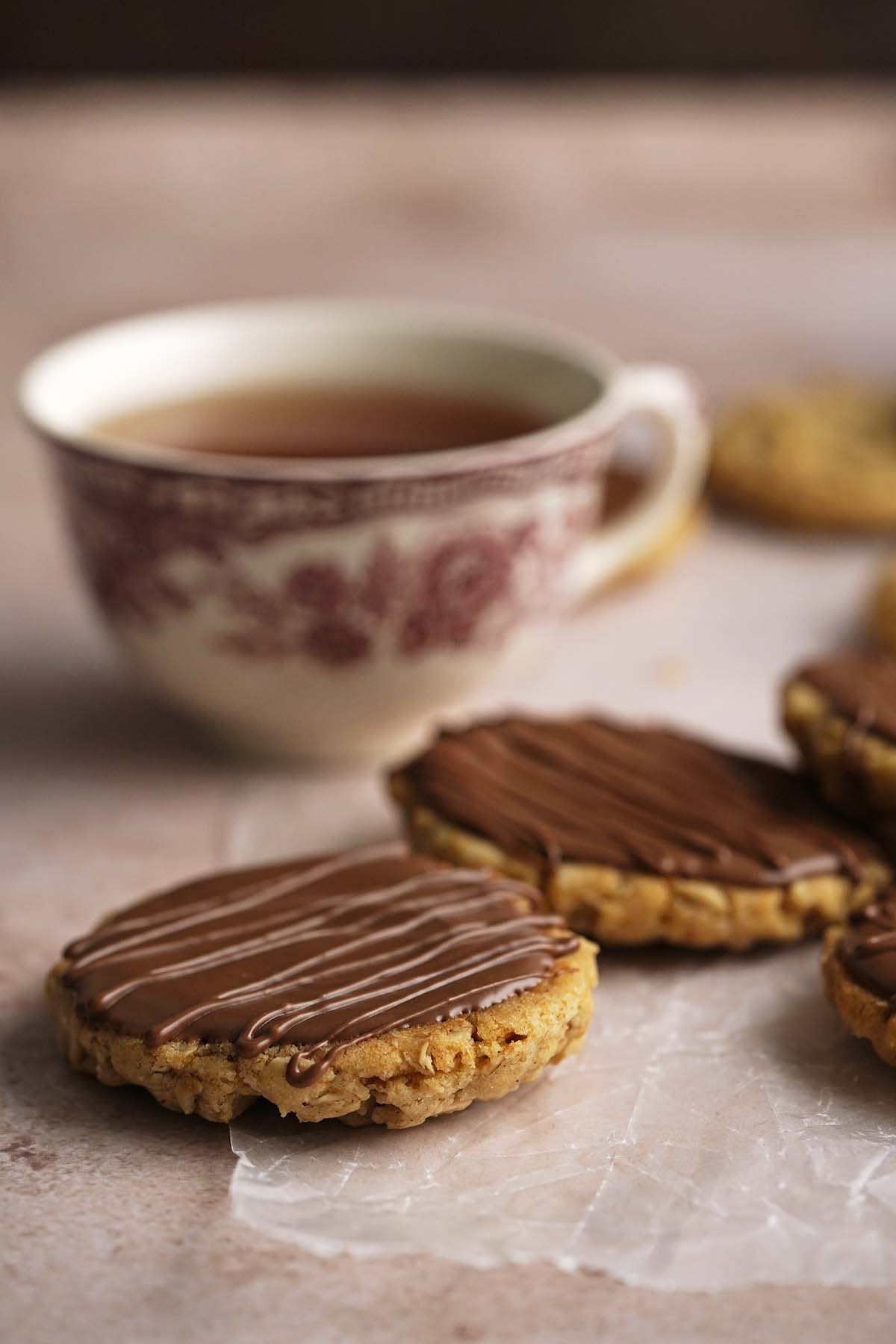 british hobnob biscuits with cup of tea in backgrounnd