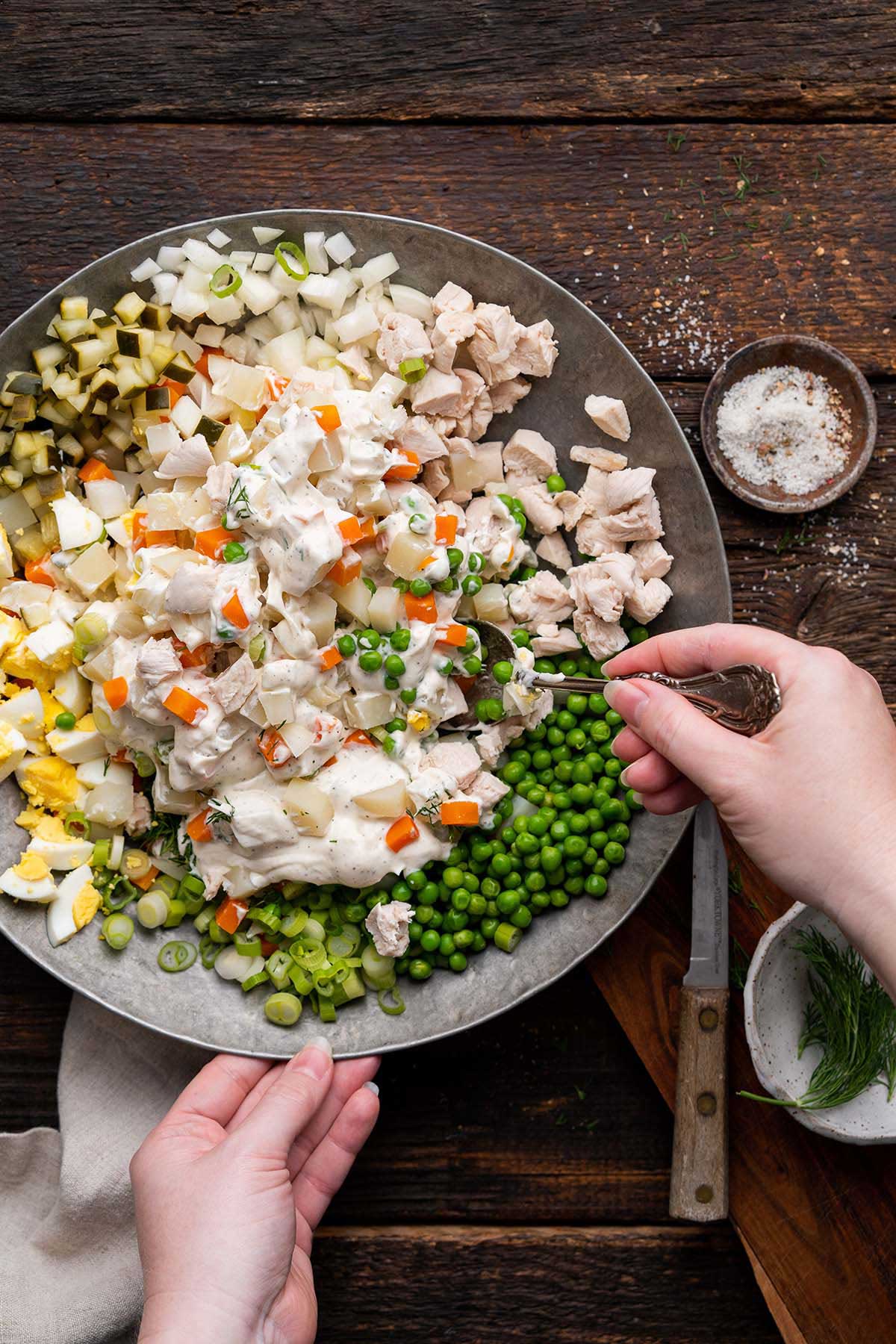 stirring creamy mayo based dressing into Russian potato salad