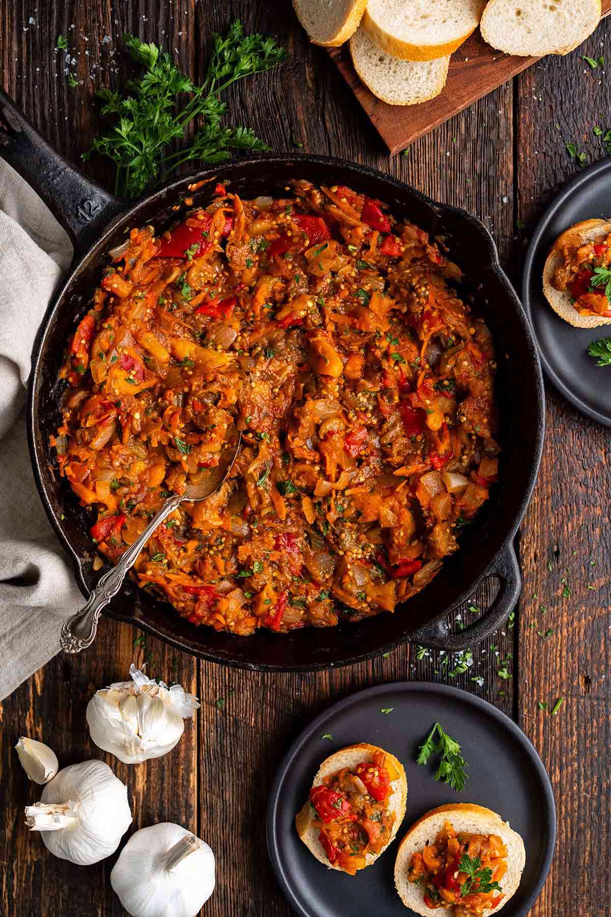 top view of cast iron skillet with Russian eggplant ikra spread with sliced bread on the side