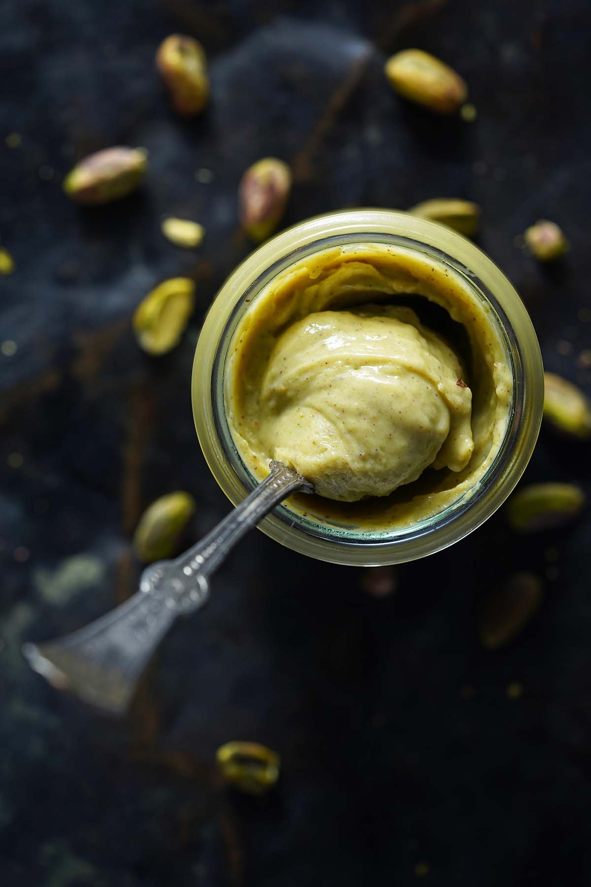 top view of pistachio cream in glass jar with vintage spoon