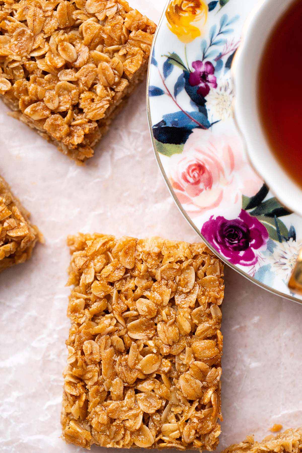 close up of classic flapjack oat bar showing texture of oats next to cup of tea