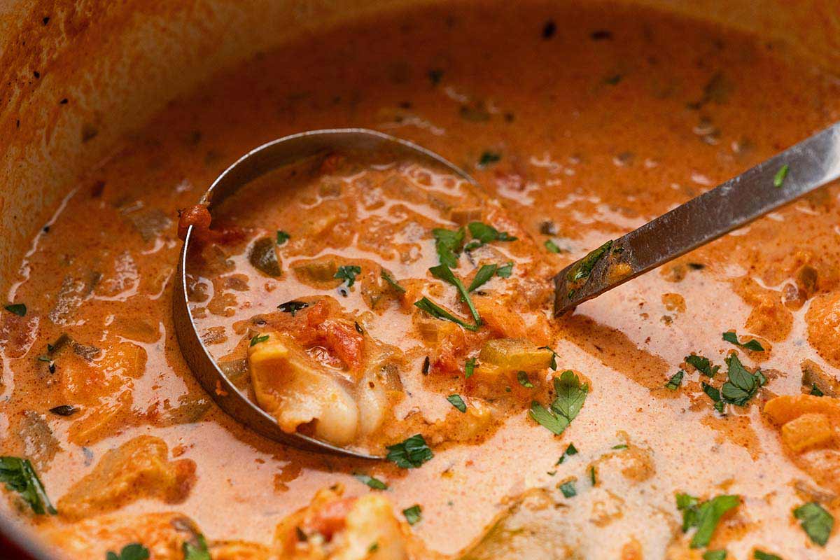 creamy seafood stew in dutch oven with ladle