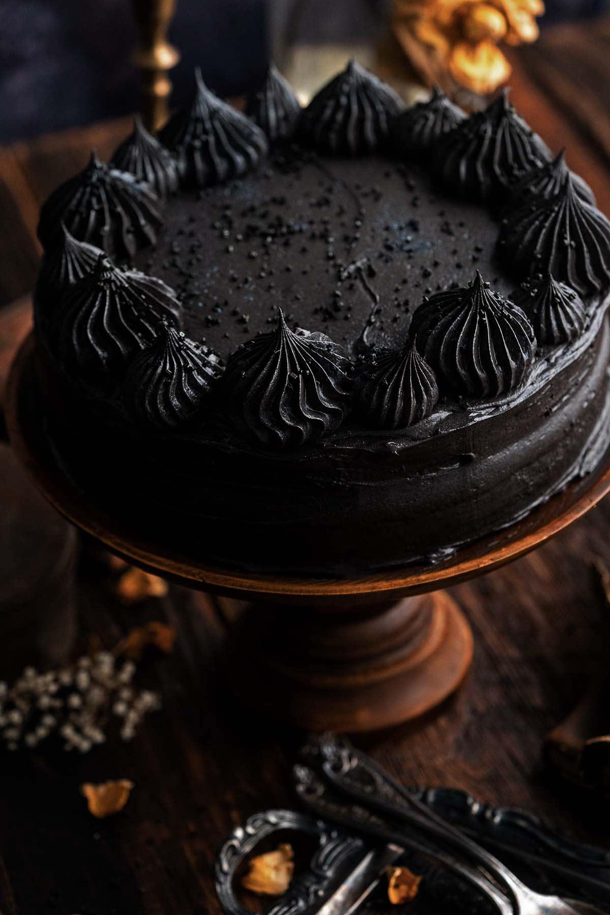black cocoa cake with chocolate buttercream on wooden cake stand with vintage forks