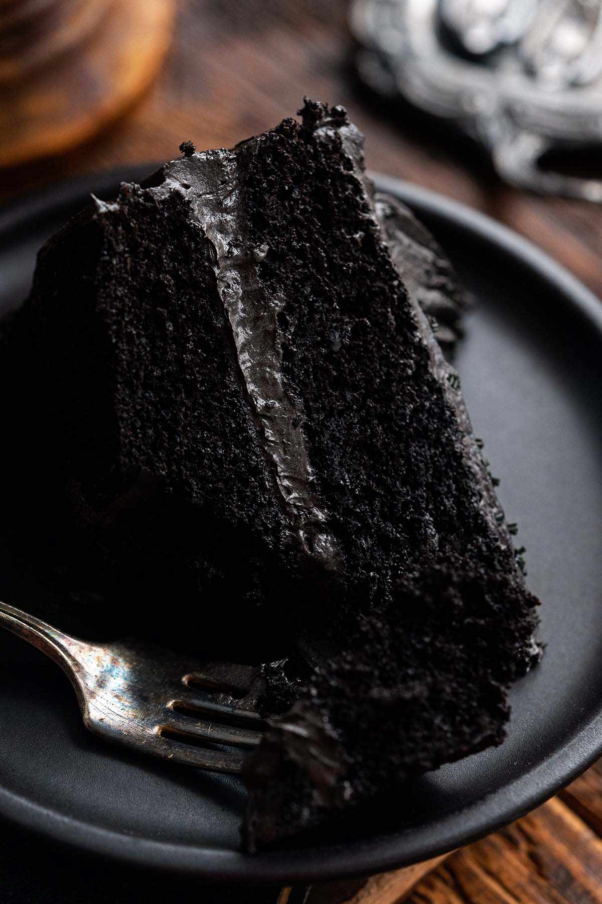 close up front view of partially eaten slice of moist black cocoa cake