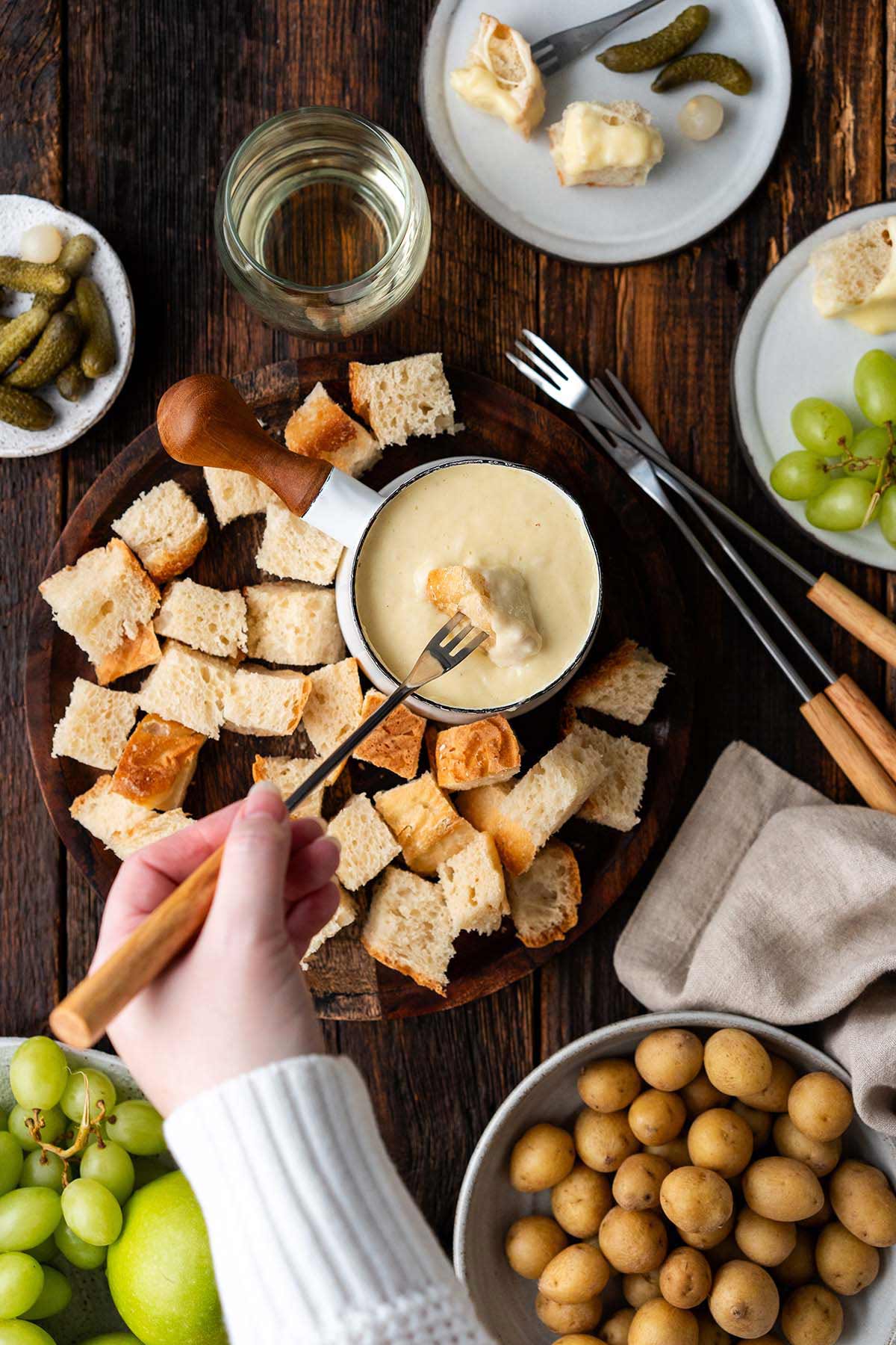 hand dipping bread into classic Swiss cheese fondue