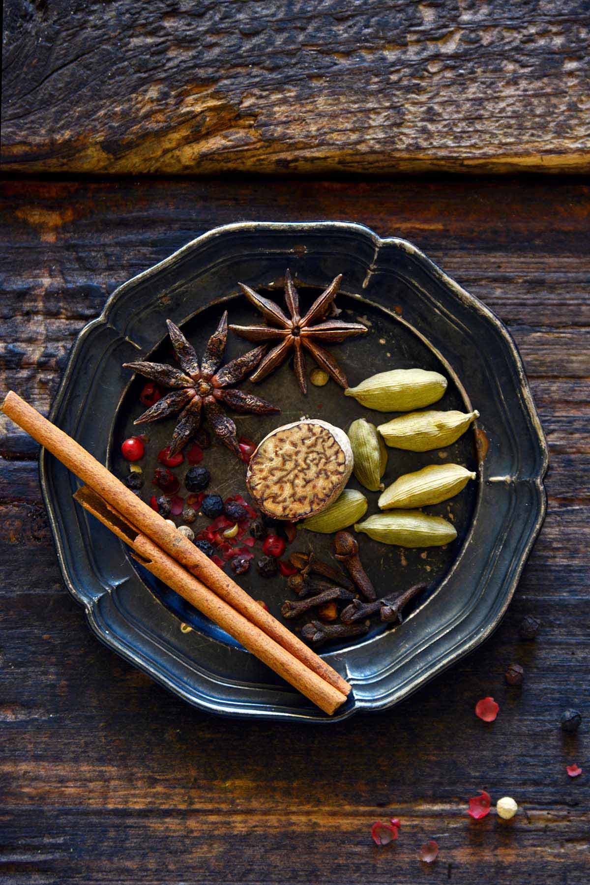 masala chai spices on small vintage silver plate on rustic wood table
