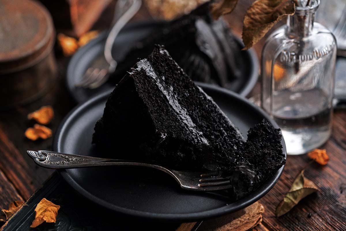 slice of black velvet cake with fudgy buttercream partially eaten with vintage fork