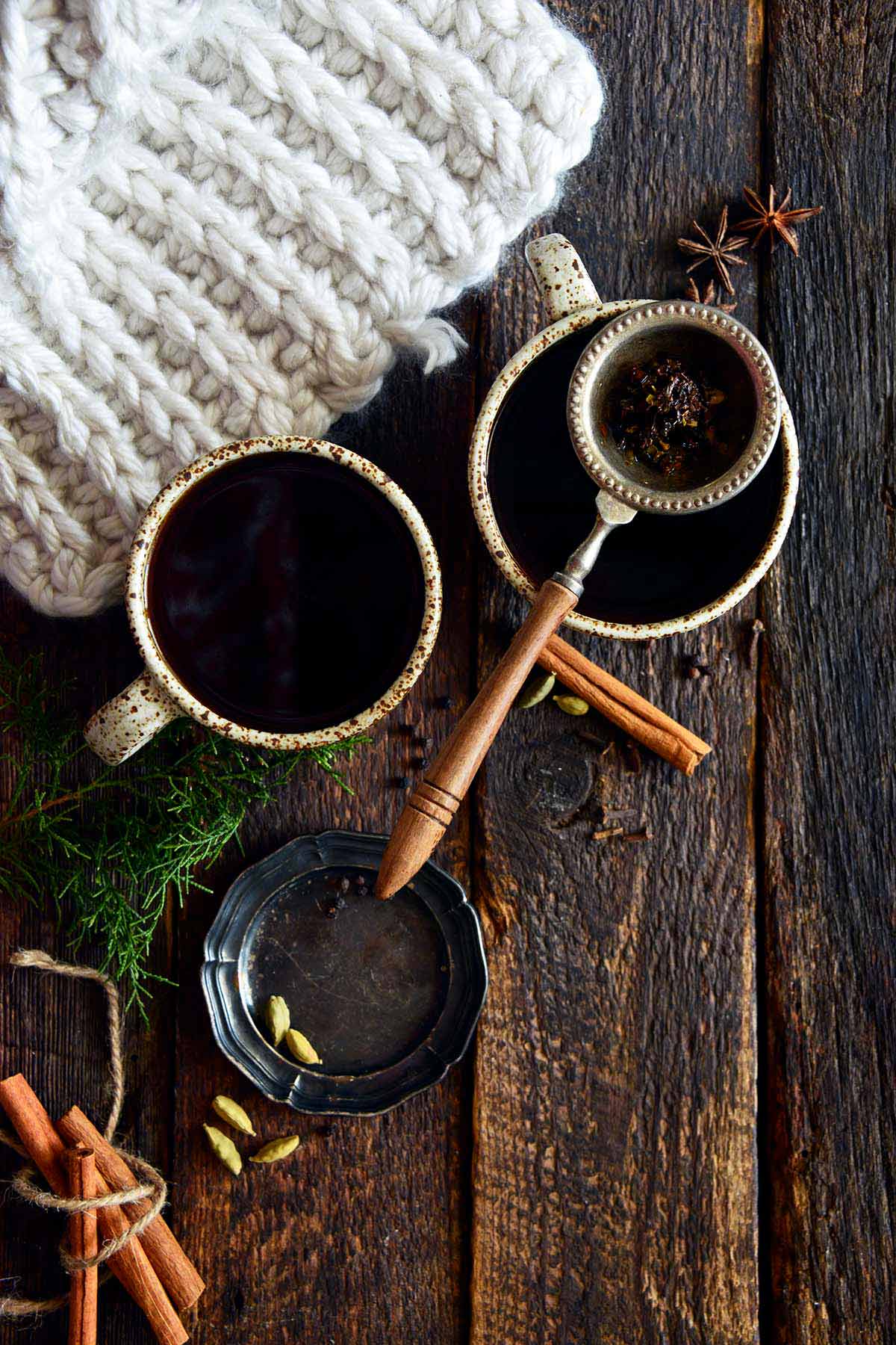 top view of mugs of masala chai on dark wooden table with cozy blanket