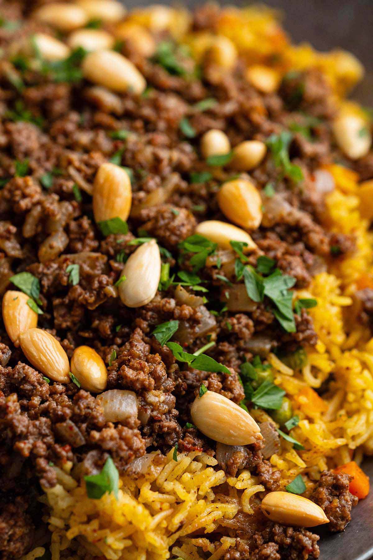 close up front view of fluffy yellow rice with spiced lamb and butter toasted nuts