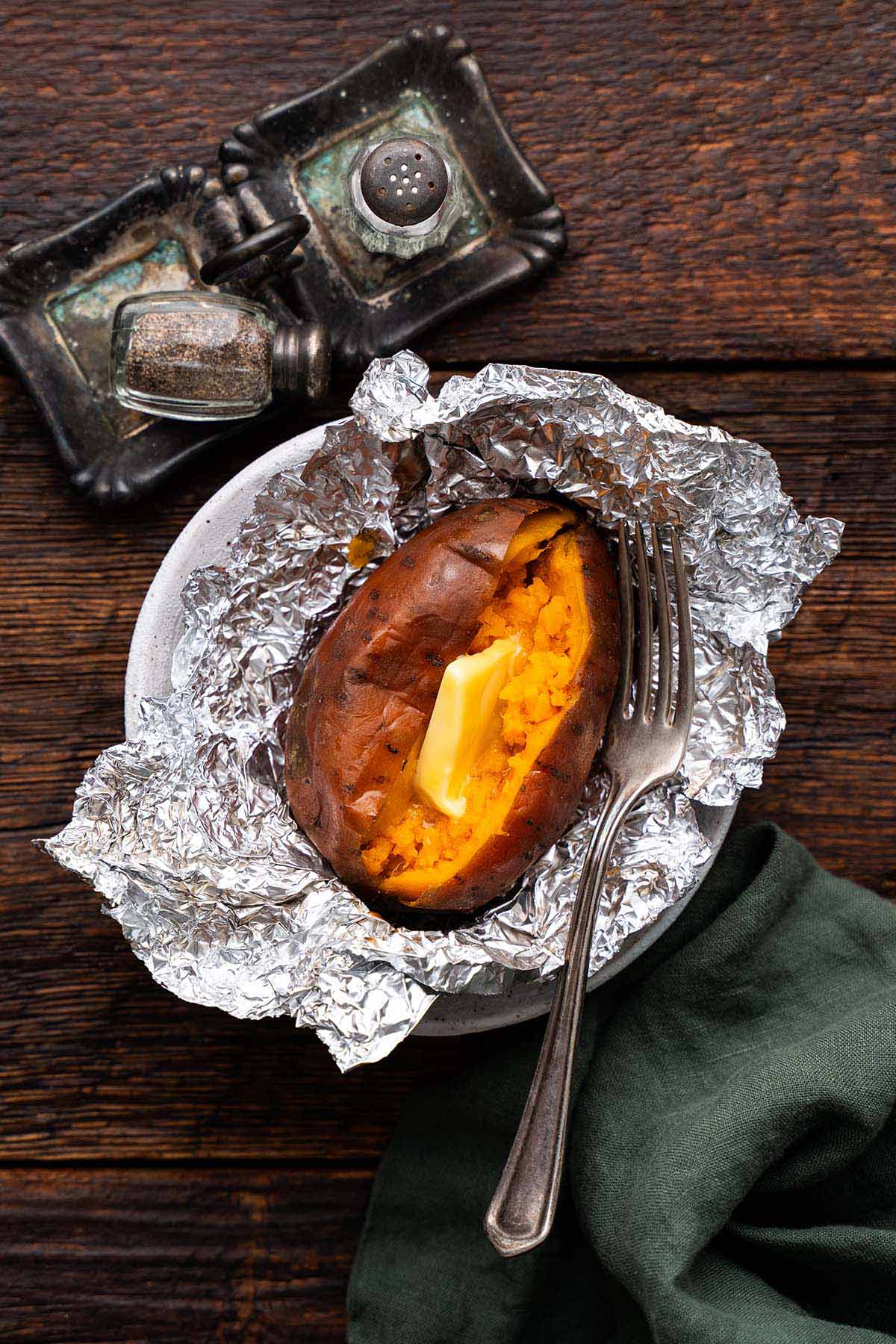 close up top view of whole sweet potato cooked in air fryer split open with a pat of butter