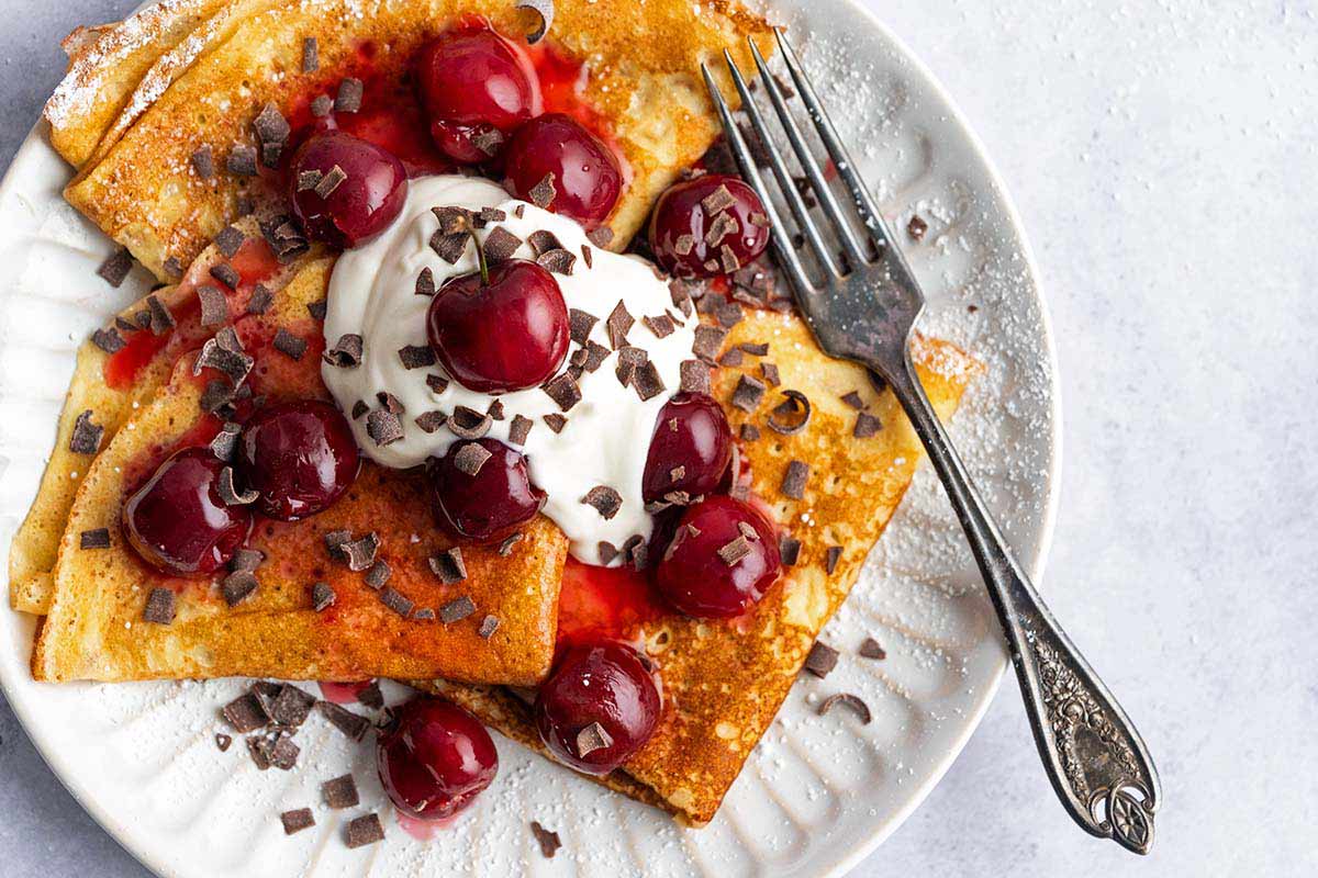 crepes with cherry topping whipped cream and chocolate